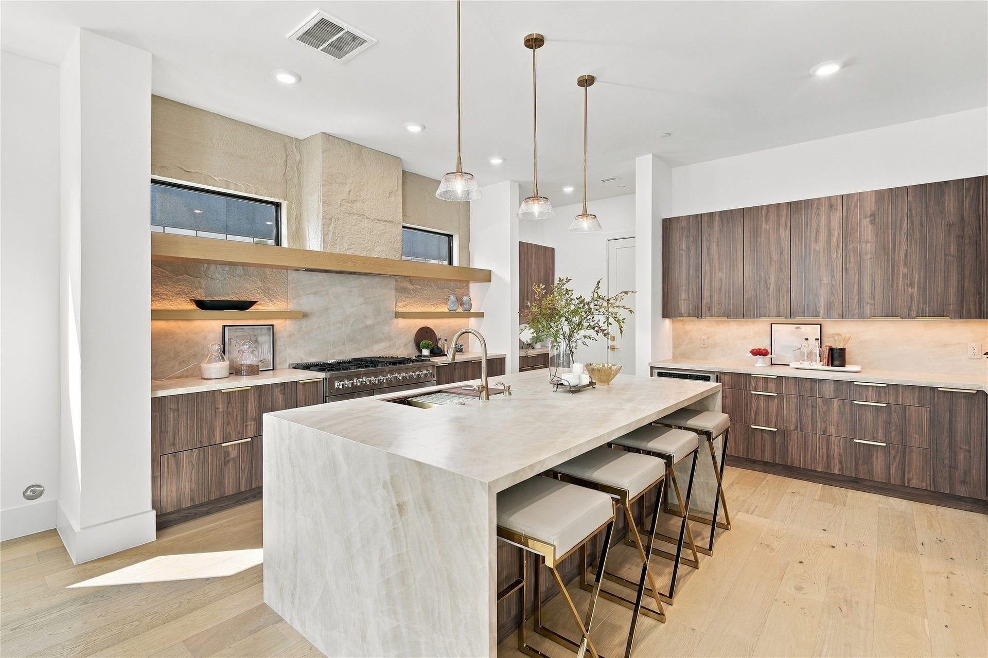Bright chef-inspired kitchen showcasing a large island, stylish pendant lighting, and high-end finishes.