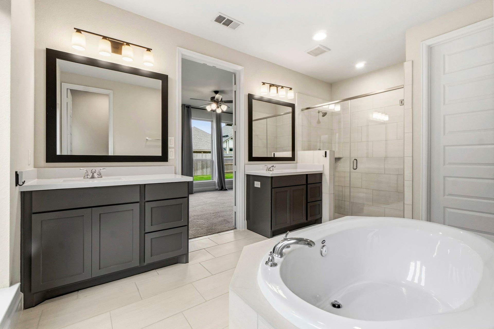 1147 Beals Creek Street, Conroe, TX 77304 The spa-inspired primary bath features dual vanities with double sinks, a relaxing soaking tub, a separate glass-enclosed shower, and two spacious walk-in closets.