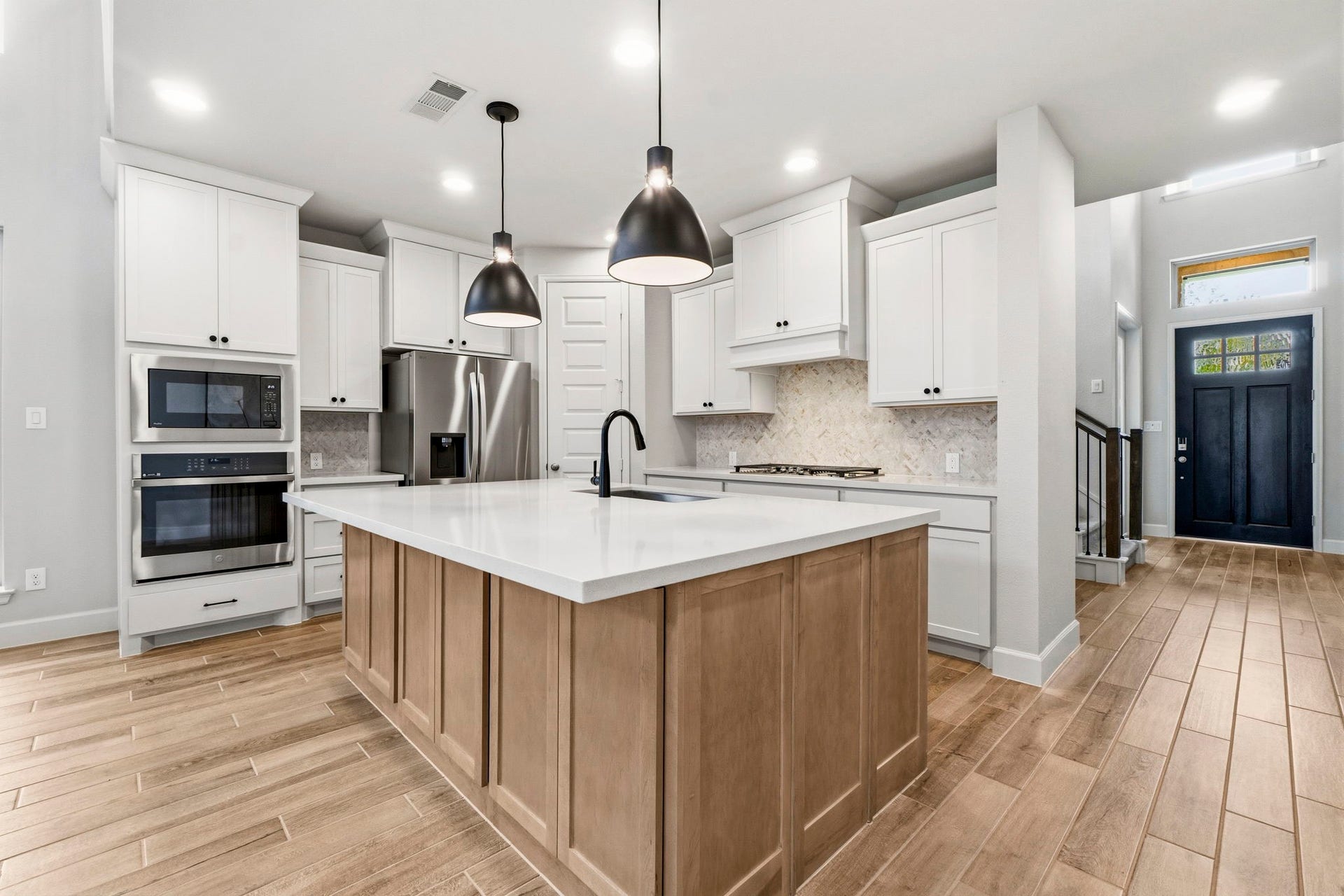 1147 Beals Creek Street, Conroe, TX 77304 The beautifully designed kitchen features elegant quartz countertops, a designer tile backsplash, 5-Burner gas stovetop, stylish pendant lighting, an oversized island with abundant storage, and ample cabinetry to keep everything organized.