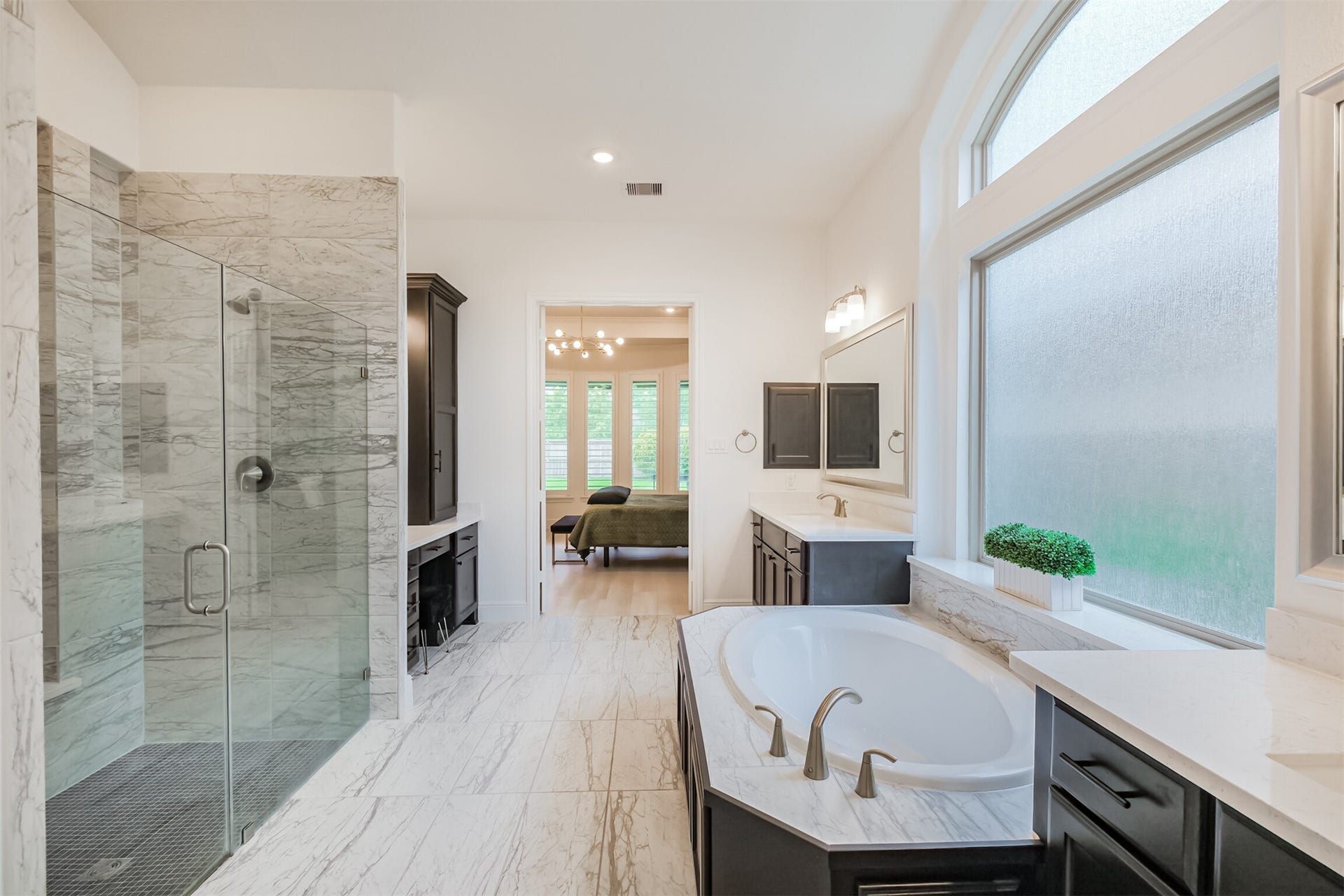 13611 Saddlebred Springs Lane, Cypress, TX 77429 Lavish primary bathroom featuring an expansive walk-in shower, a grand soaking tub, and sleek dual vanities. Oversized frosted windows bathe the space in natural light while maintaining privacy, creating a serene, spa-inspired retreat.