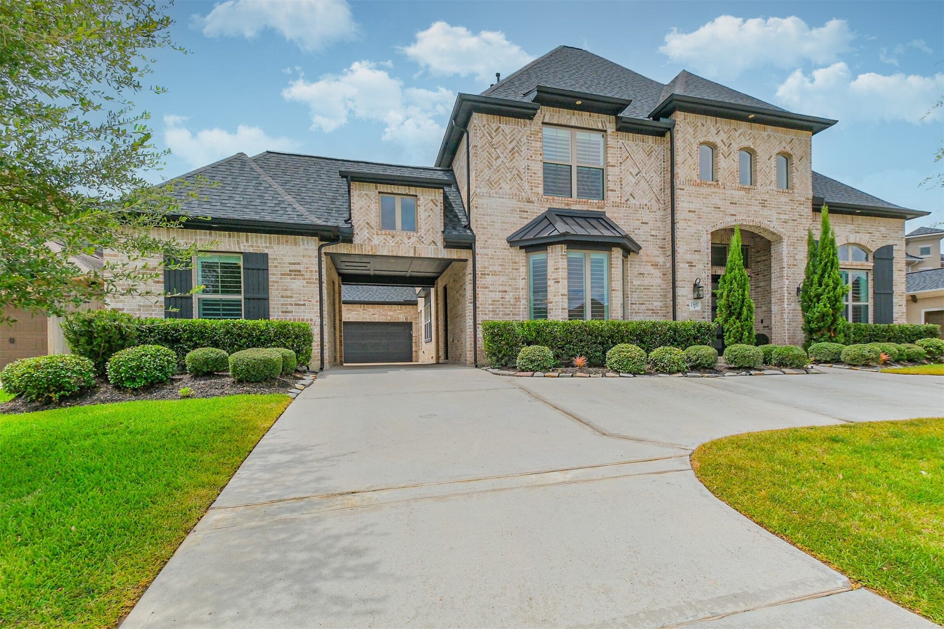 13611 Saddlebred Springs Lane, Cypress, TX 77429 Stunning two-story brick home with elegant architectural details, manicured landscaping, and a spacious 'U' driveway leading to a charming porte-cochre.