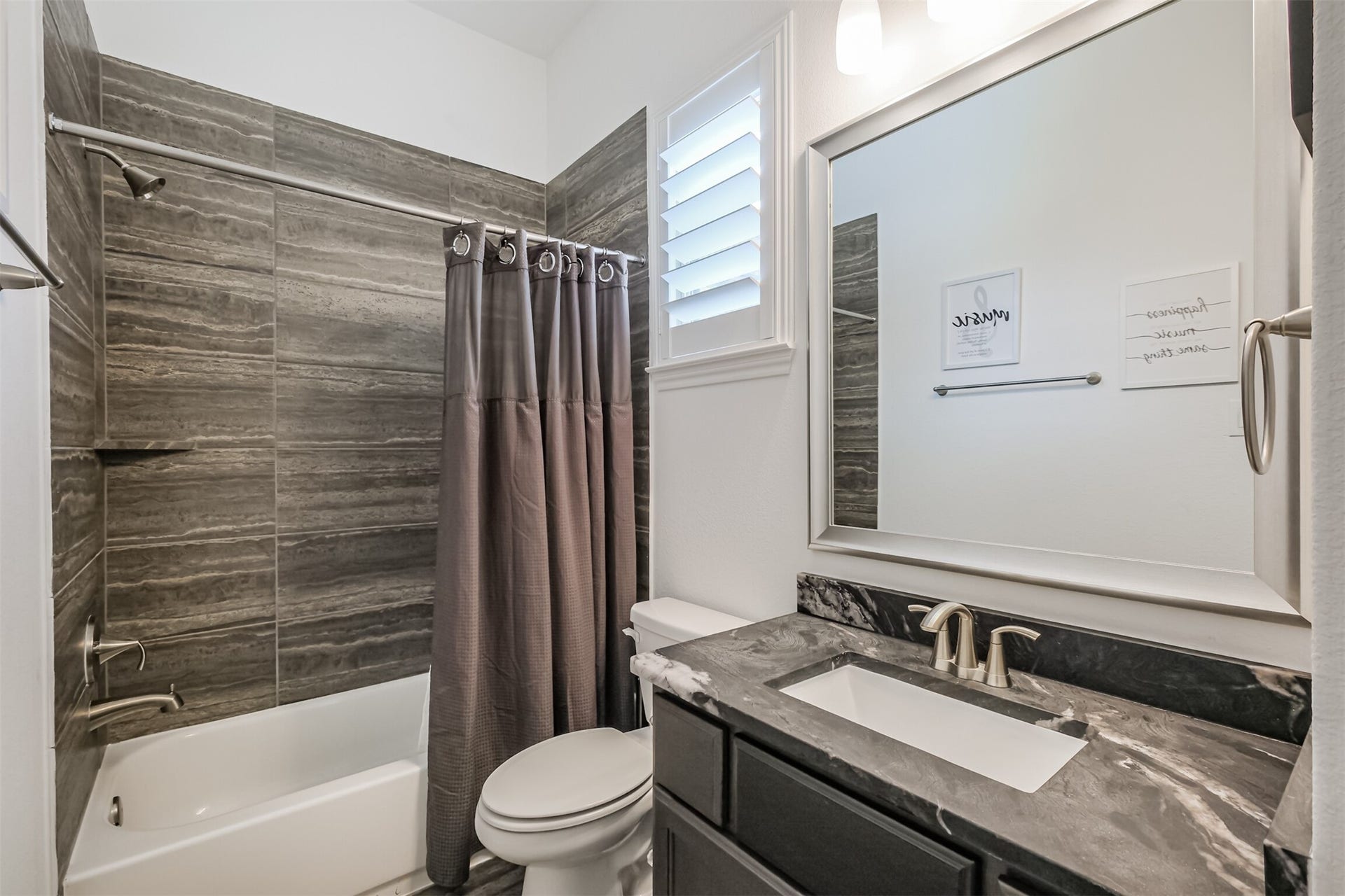 13611 Saddlebred Springs Lane, Cypress, TX 77429 Well-appointed secondary bathroom within the private guest suite, featuring a sleek vanity with an elegant marble countertop, contemporary mirror, and a stylish shower-tub combination accented by modern tileworkoffering guests both comfort and privacy.