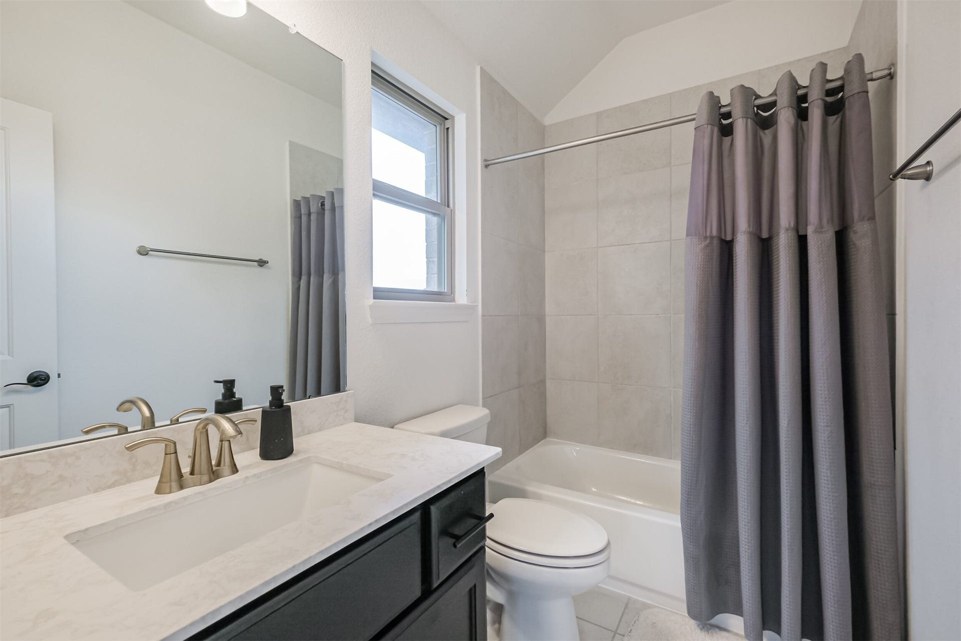 13611 Saddlebred Springs Lane, Cypress, TX 77429 Sophisticated second primary bathroom featuring a sleek contemporary vanity accented with elegant brass fixtures, an expansive mirror, and a beautifully tiled shower-tub combination, creating a polished and inviting private retreat.