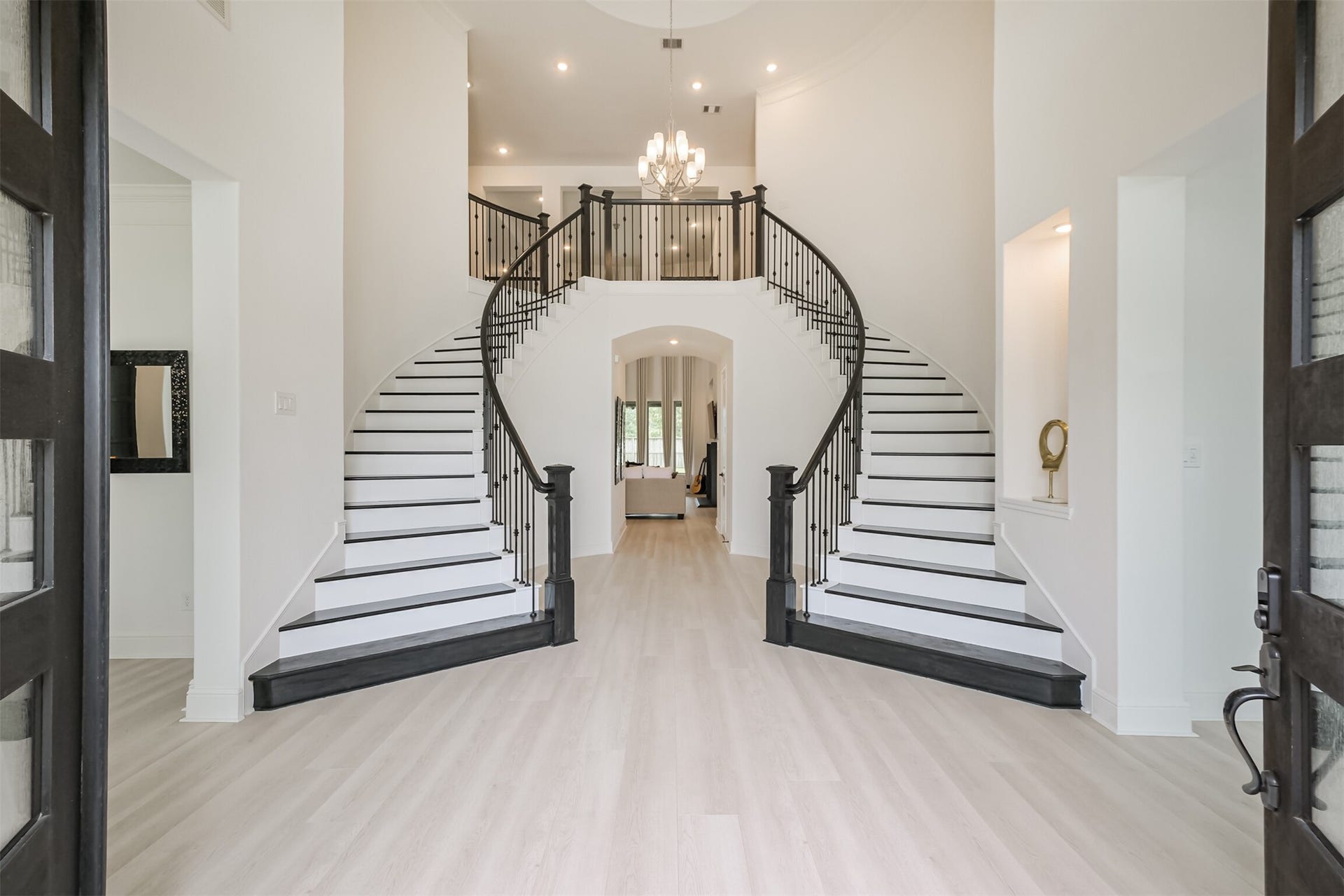 13611 Saddlebred Springs Lane, Cypress, TX 77429 Impressive grand foyer featuring custom dual sweeping staircases, elegant chandelier lighting, and a bright, expansive layout that creates a breathtaking grand entrance the moment you step inside.