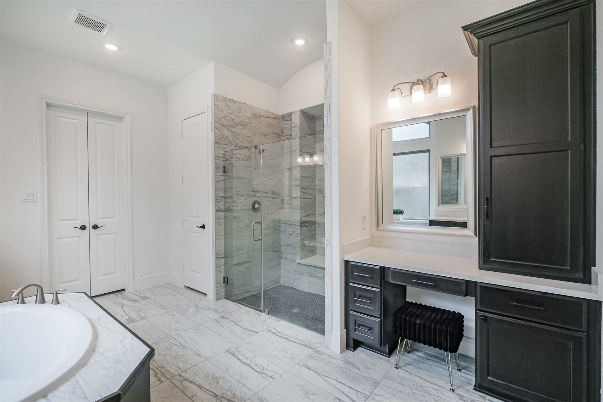 13611 Saddlebred Springs Lane, Cypress, TX 77429 Spa-inspired primary bathroom featuring an expansive glass-enclosed walk-in shower, luxurious soaking tub, and elegant marble tile flooring. A dedicated private vanity area and generous storage add both function and sophistication, creating a serene, resort-like retreat.