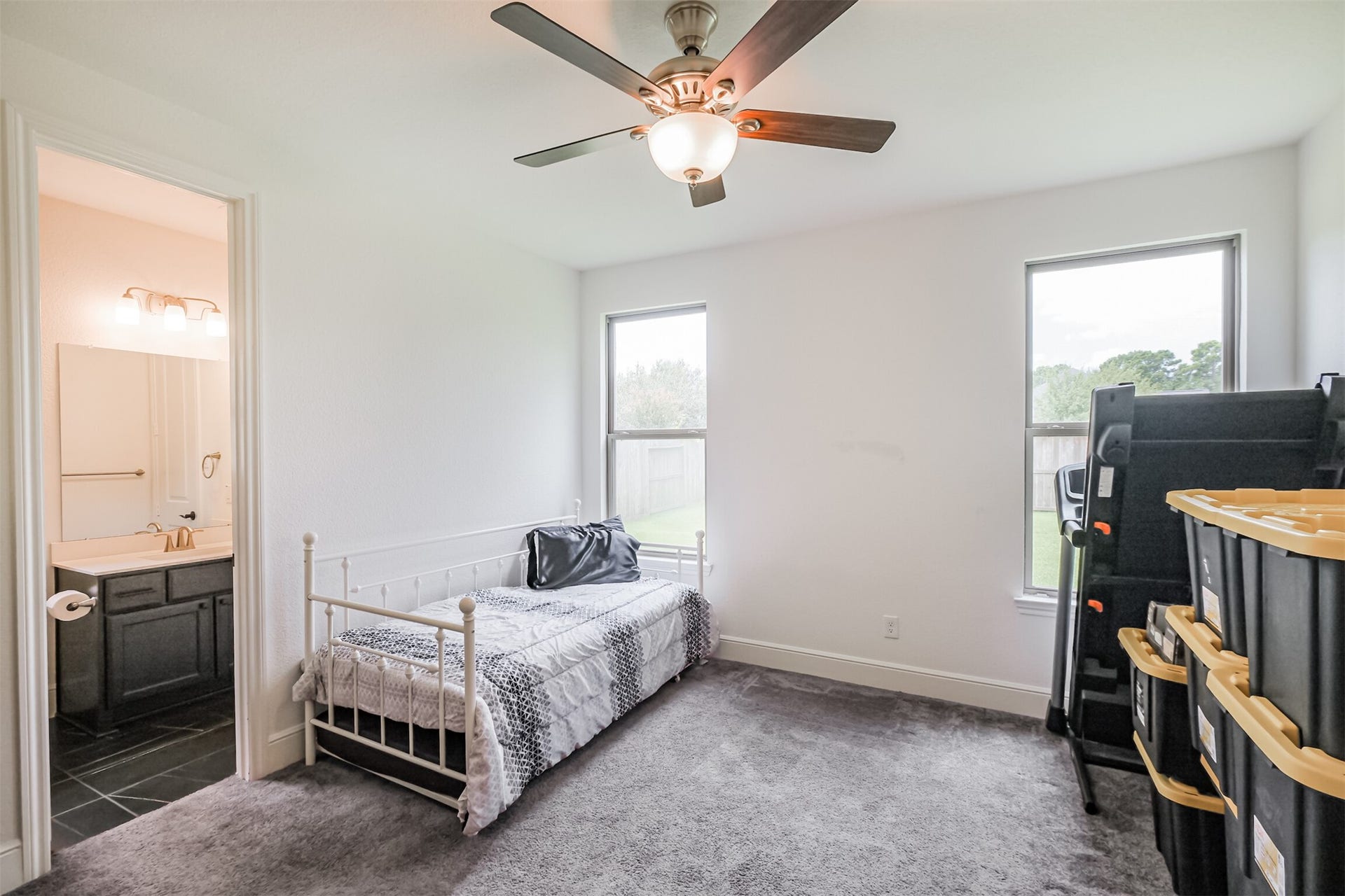 13611 Saddlebred Springs Lane, Cypress, TX 77429 Bright and inviting downstairs guest suite/third bedroom featuring expansive windows that fill the space with natural light, a ceiling fan for added comfort, and a private en-suite bathroom, creating a comfortable and secluded retreat for guests.