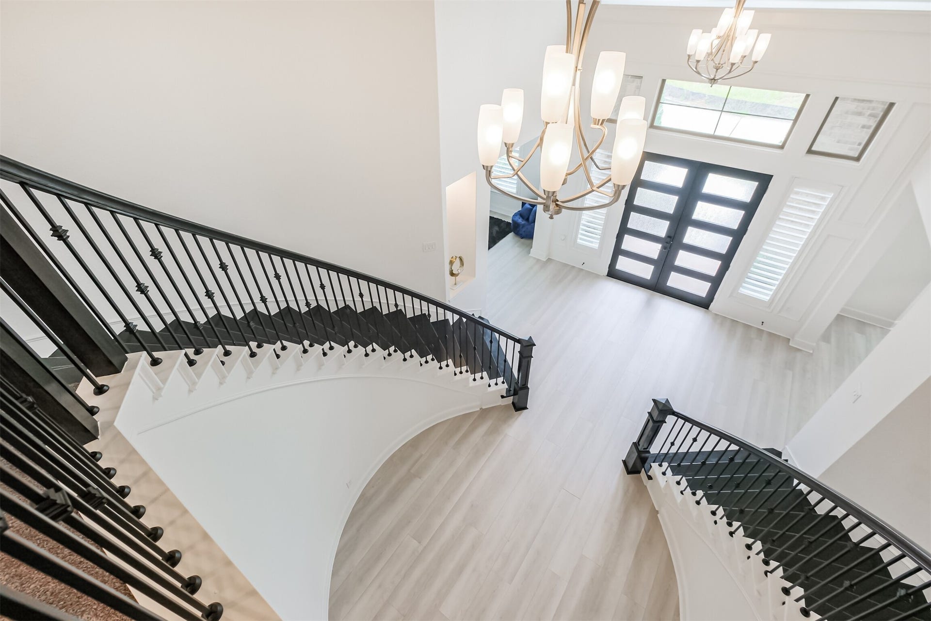 13611 Saddlebred Springs Lane, Cypress, TX 77429 Grand foyer with a sweeping dual staircase, modern chandelier, and elegant double doors, exuding luxury and sophistication.