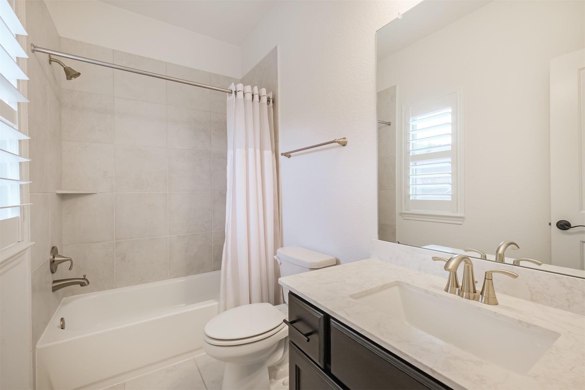 13611 Saddlebred Springs Lane, Cypress, TX 77429 Bright and contemporary seventh en-suite bathroom featuring a sleek vanity, elegant fixtures, and a beautifully tiled tub and shower combination. Clean lines and modern finishes create a polished, tranquil retreat.