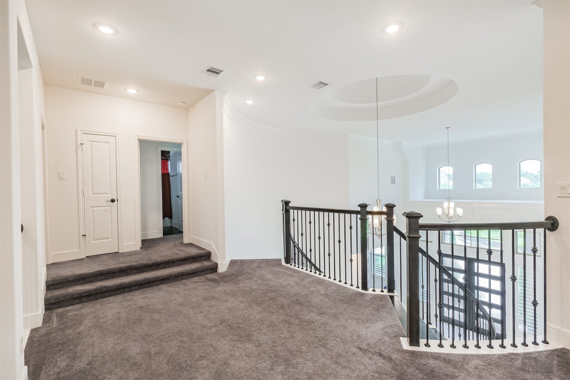13611 Saddlebred Springs Lane, Cypress, TX 77429 Expansive upper-level landing featuring elegant wrought-iron railings, plush carpeting, and oversized windows that fill the space with abundant natural light, creating a graceful transition between the homes upstairs living areas.