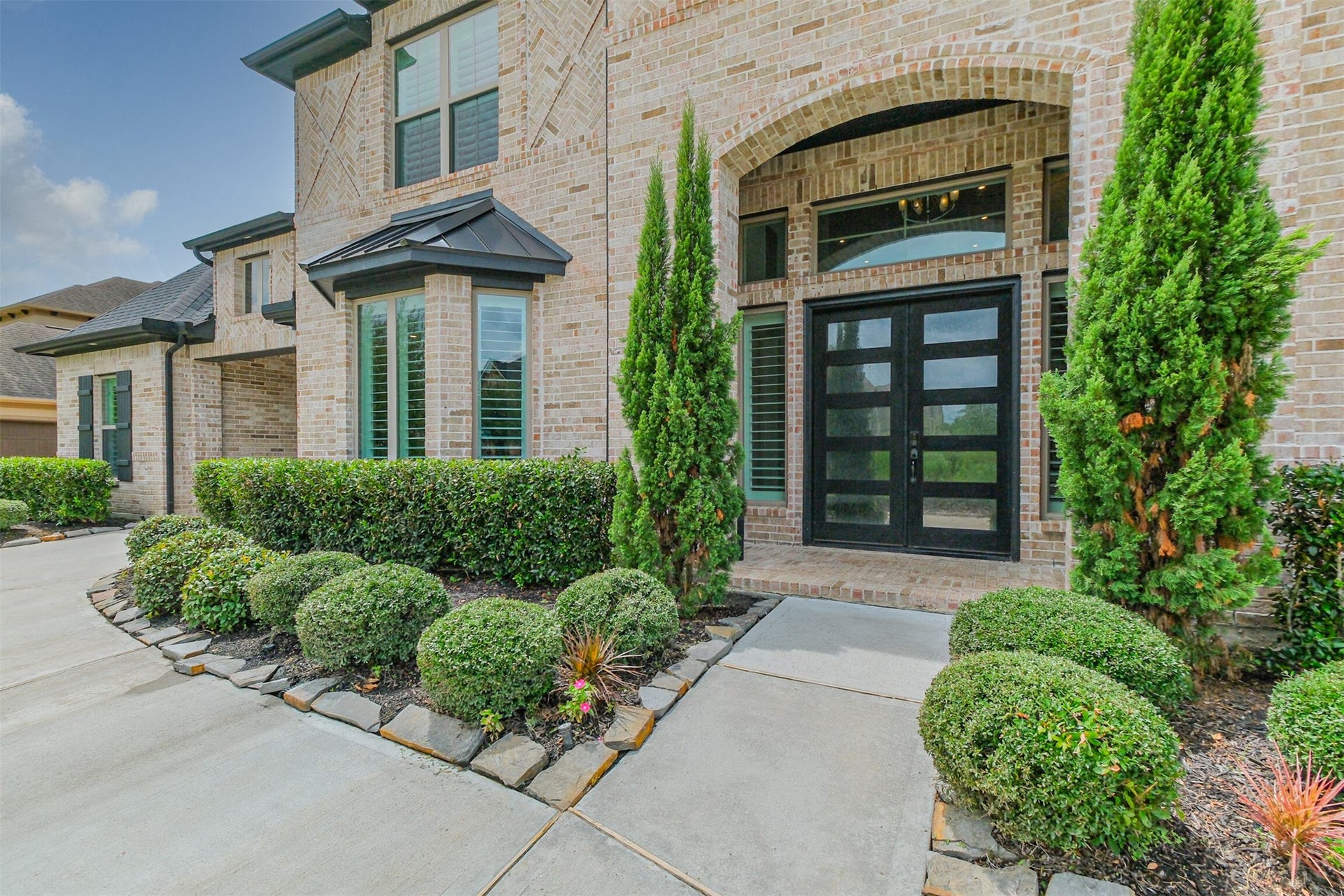 13611 Saddlebred Springs Lane, Cypress, TX 77429 Stunning brick faade featuring elegant double front doors, energy-efficient double-pane windows, and tall, lush greenery complemented by meticulously maintained landscaping for exceptional curb appeal.