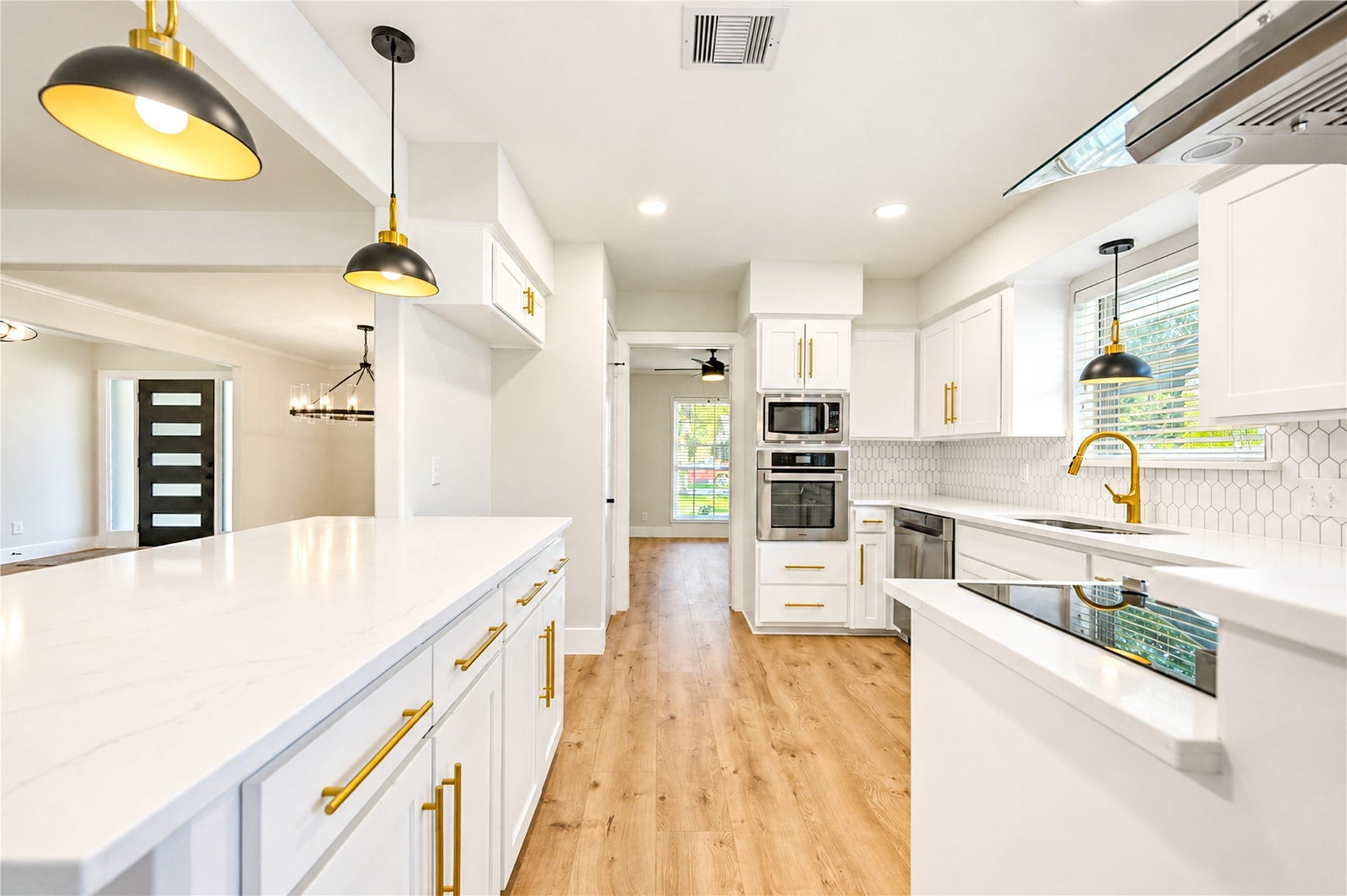 10607 Del Monte Drive, Houston, TX 77042 Stunning remodeled kitchen opens seamlessly to the family room and features a breakfast bar with seating for barstools, white cabinetry, quartz countertops, designer backsplash, stainless steel appliances, elegant gold accents, and all-new designer lighting.