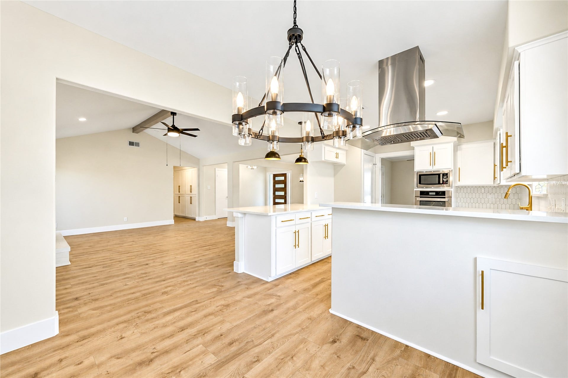 10607 Del Monte Drive, Houston, TX 77042 Thoughtfully remodeled kitchen opens to the dining and living areas, featuring elegant white cabinetry, gold hardware, designer lighting, and generous counter space.