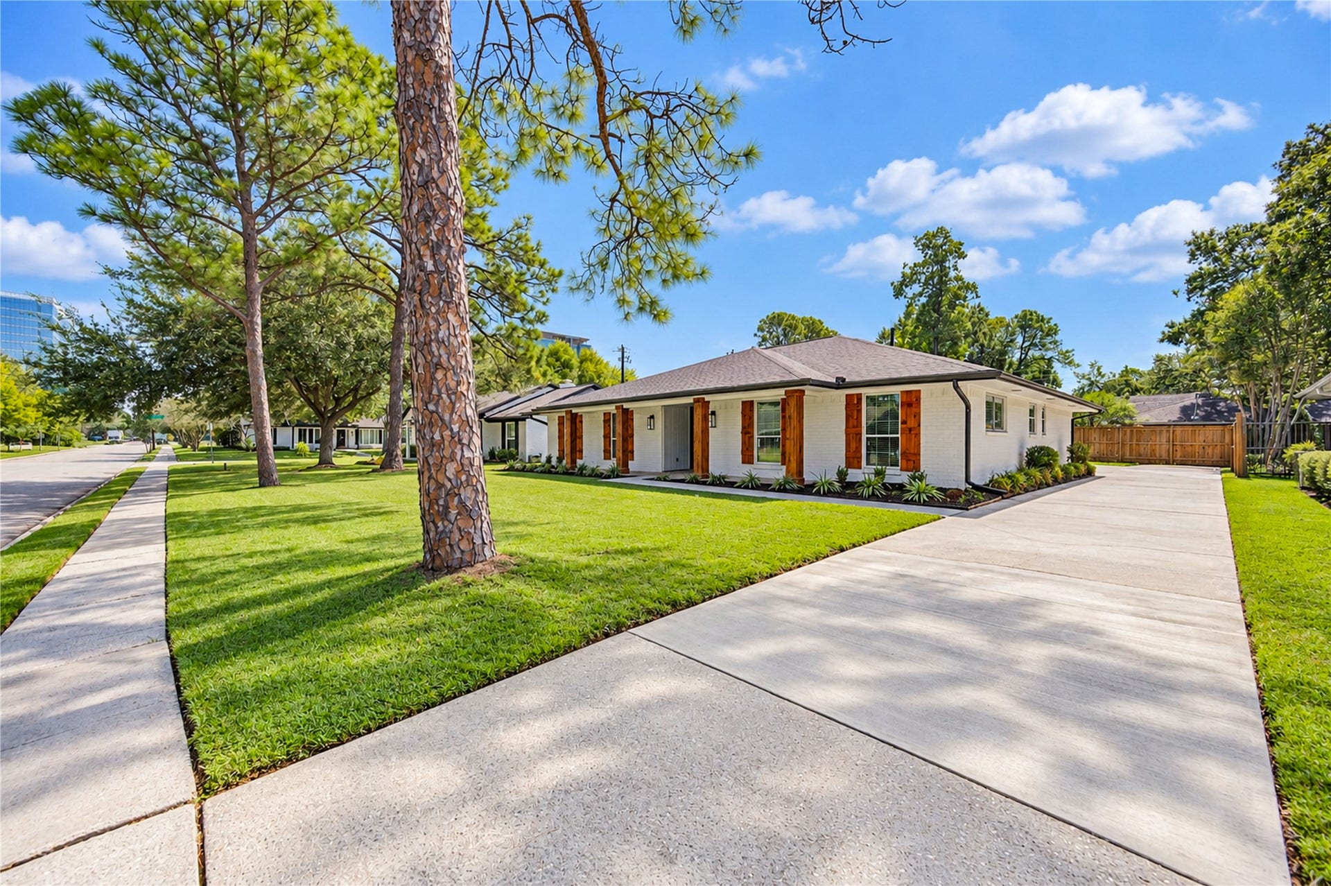 10607 Del Monte Drive, Houston, TX 77042 Expansive front lawn with mature shade trees, a new front sidewalk, and a long driveway leading to additional rear parking and garage.