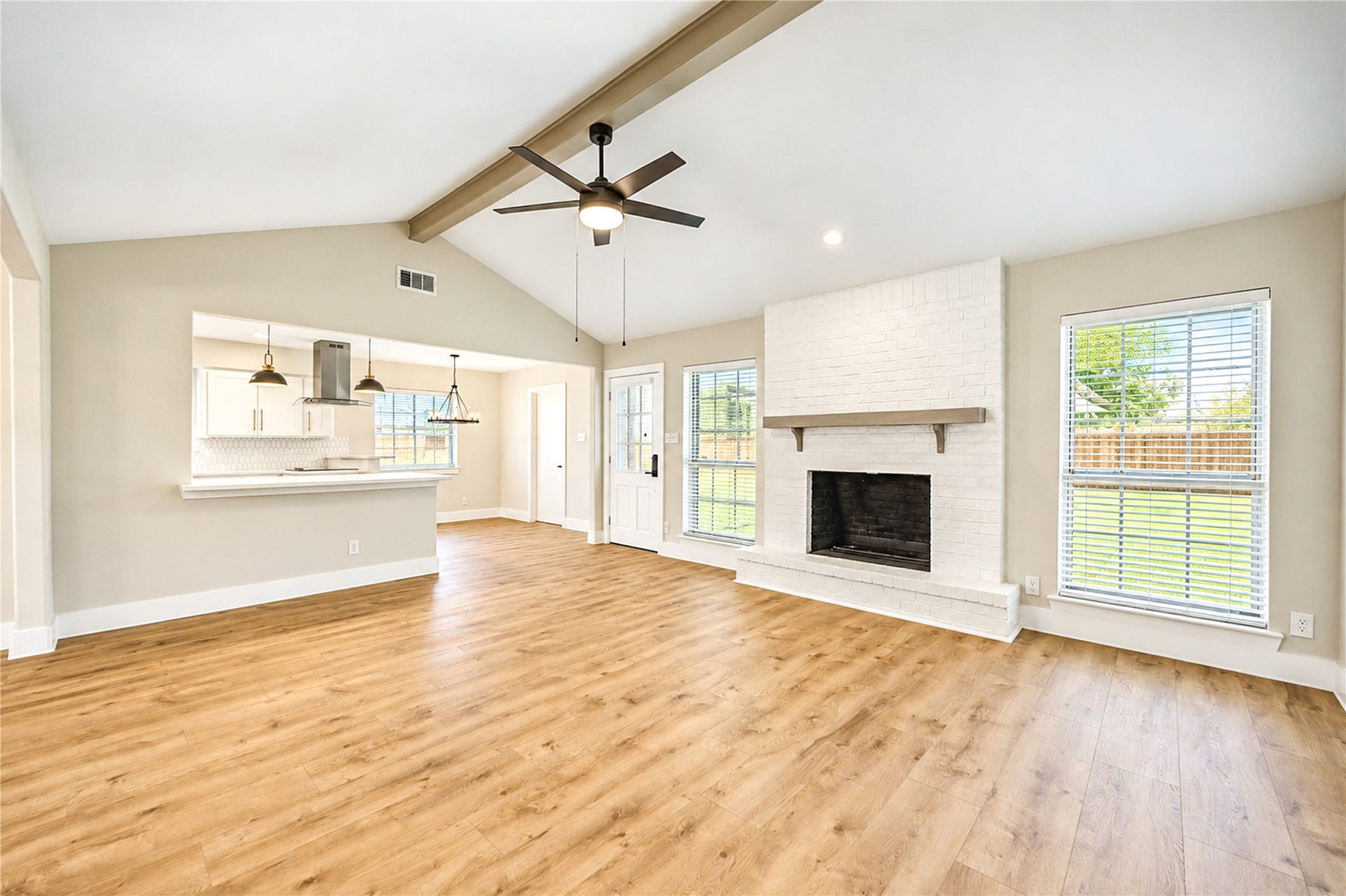 10607 Del Monte Drive, Houston, TX 77042 Spacious family room features vaulted ceilings, decorative wood beam, stylish fireplace, new ceiling fan, and gorgeous wide-plank engineered wood flooring.