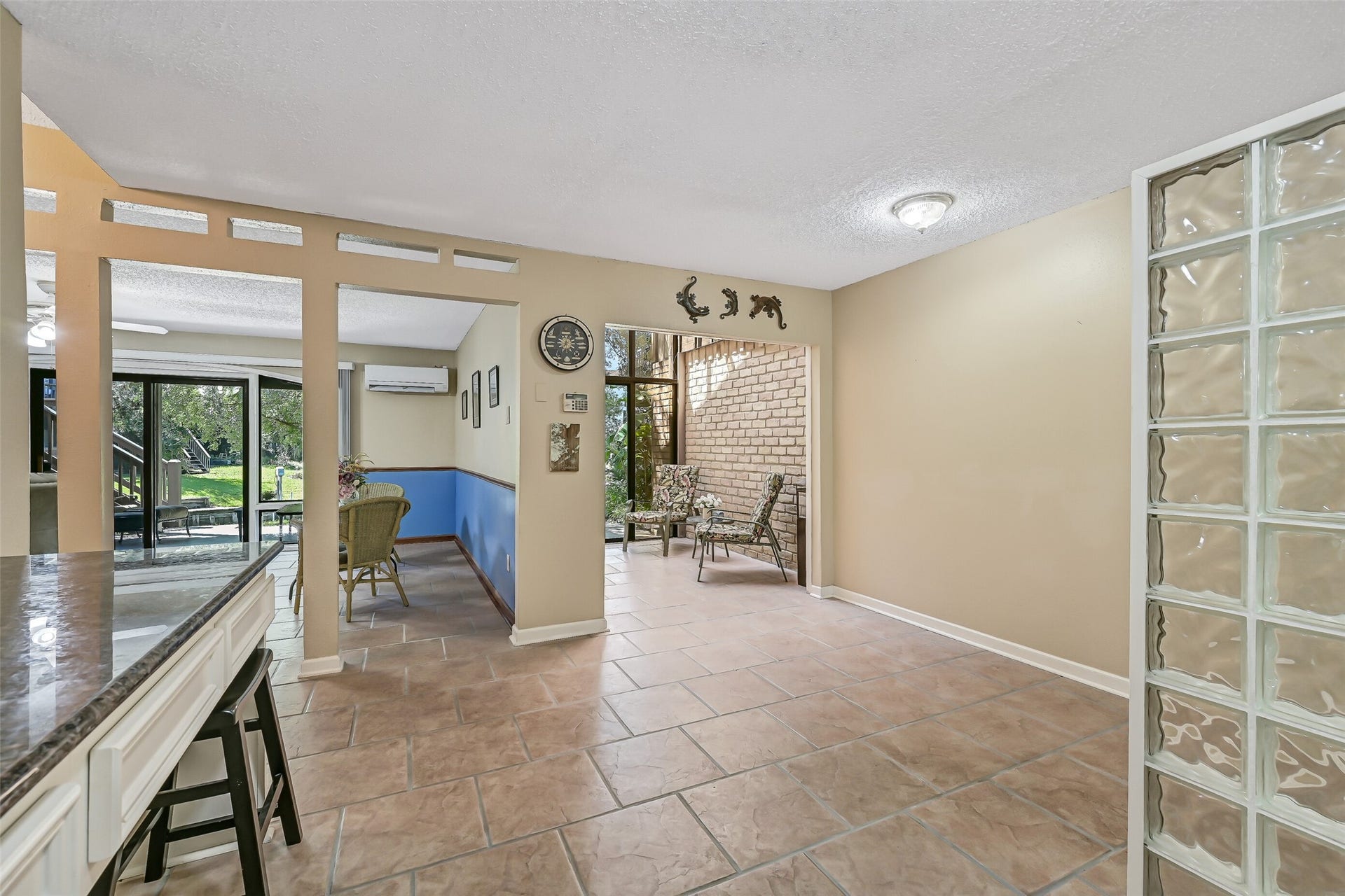 18214 Bal Harbour Drive, Nassau Bay, TX 77058 Looking across the ground-floor guest kitchen reveals the flexible layout, with a breakfast bar, durable 12" x 12" tile flooring & distinctive glass-block partition. Beyond are the two-story sunroom and separate living/game room, providing multiple spaces for dining, relaxing or accommodating extended-stay guests.