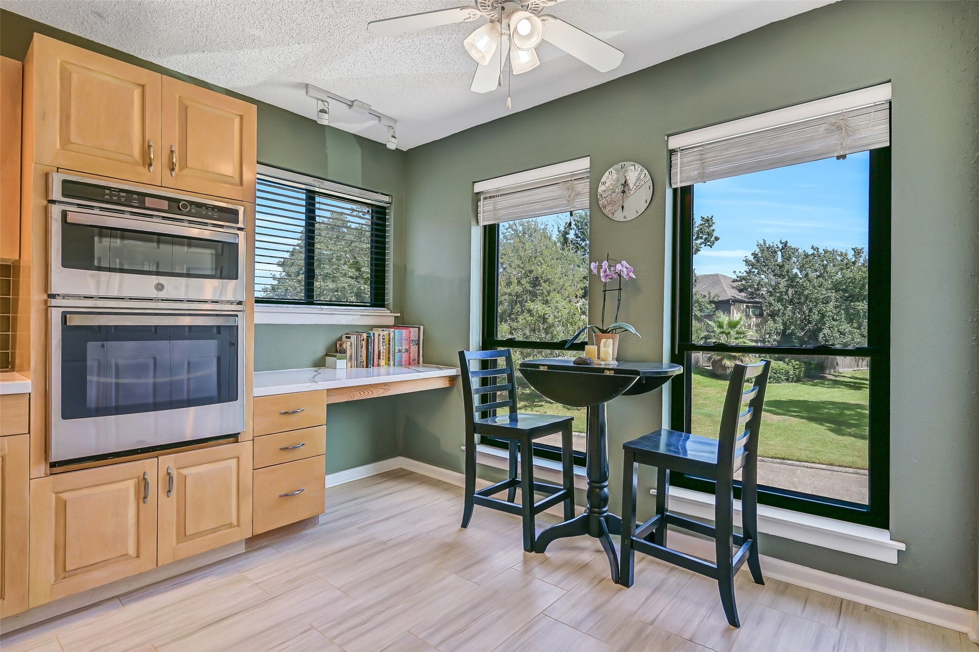 18214 Bal Harbour Drive, Nassau Bay, TX 77058 Tucked beside the kitchen's built-in GE ovens, this bright breakfast area features a built-in desk with drawers, additional counter space & windows overlooking the park-like greenspace across the street. Mature trees and open grassy areas create a pleasant view with no townhomes directly in front.