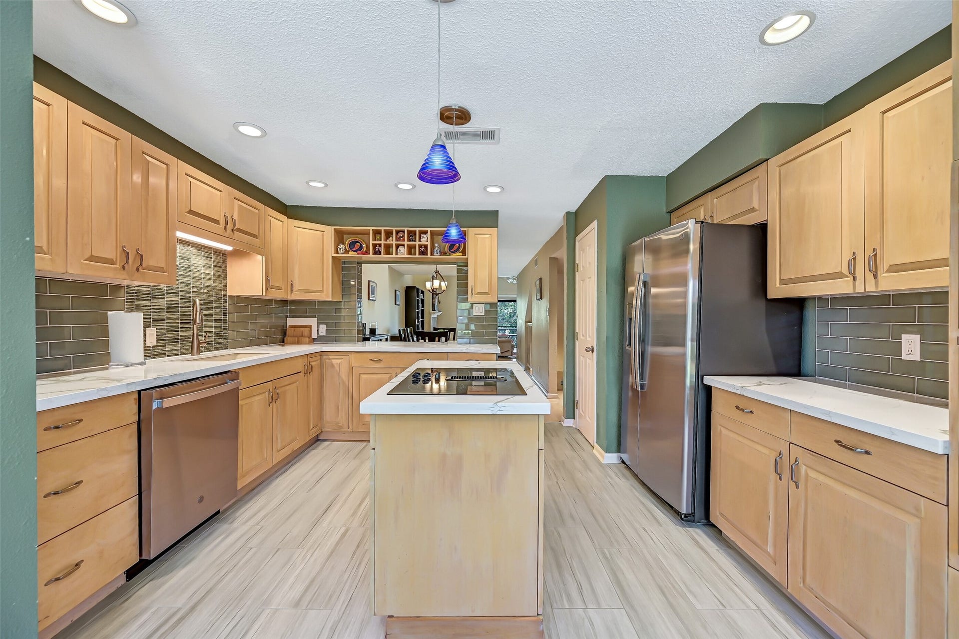 18214 Bal Harbour Drive, Nassau Bay, TX 77058 The remodeled second-floor kitchen features quartz countertops, blonde oak cabinetry, seafoam-green subway & glass tile backsplash, recessed lighting, and an island with GE Profile electric cooktop & downdraft ventilation. Stainless steel GE appliances were replaced in 2024, including the refrigerator, dishwasher & ovens.