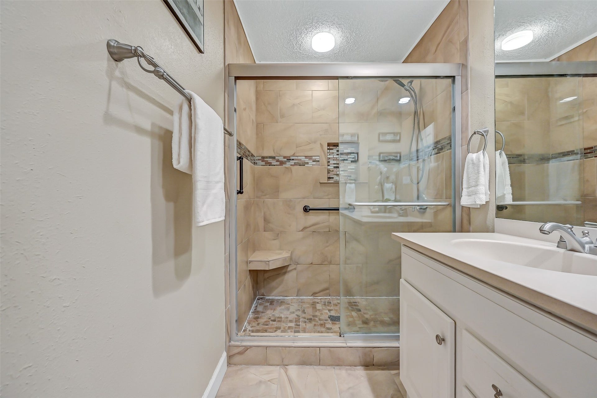 18214 Bal Harbour Drive, Nassau Bay, TX 77058 A closer look at the remodeled shower reveals its tiled surround with decorative glass-tile ribbon, recessed toiletry niche, built-in bench & 1" x 1" tiled shower floor. A glass enclosure, handheld shower wand, grab bars & comfort-height toilet complete this well-appointed second-floor bathroom.