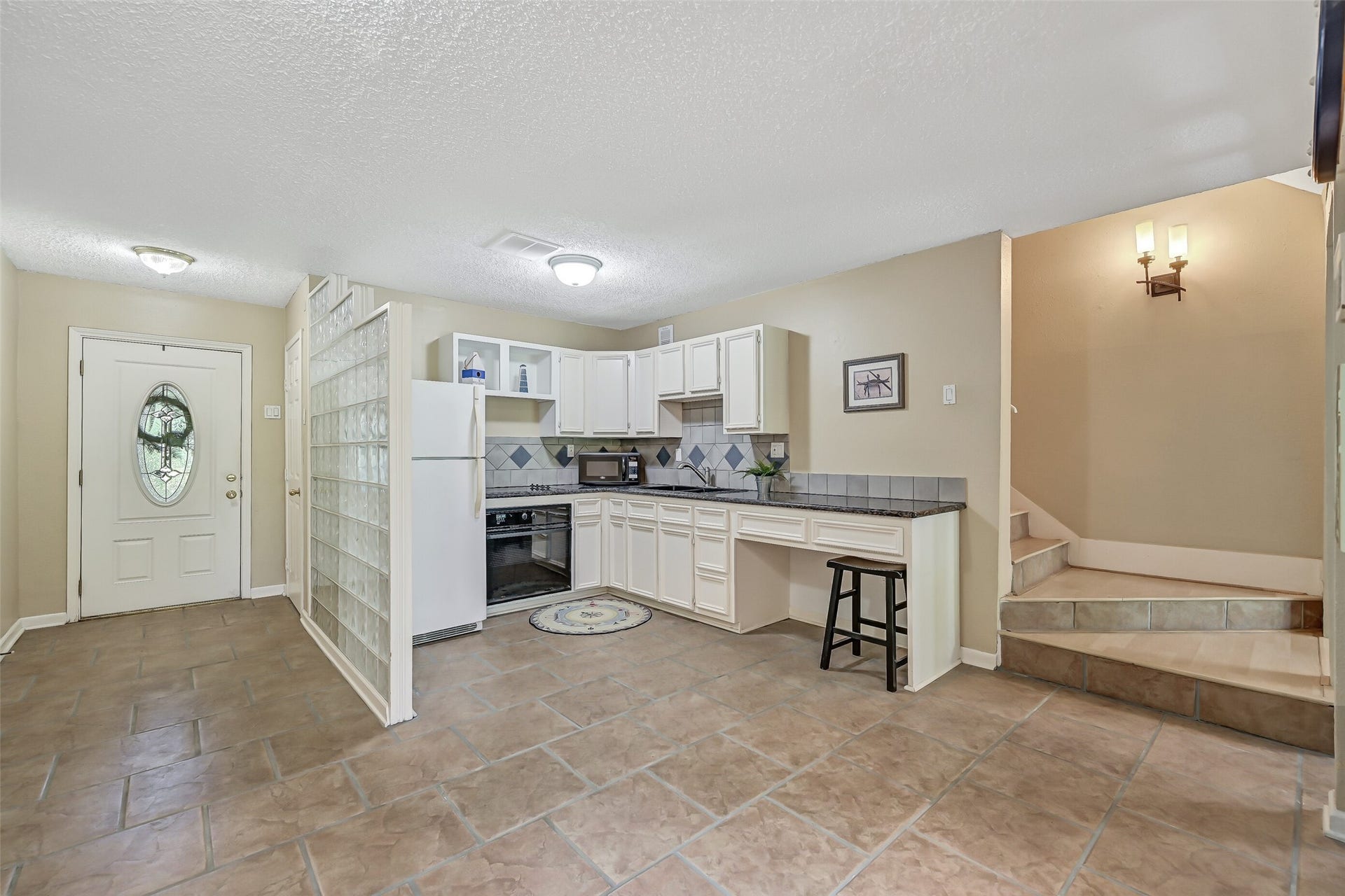 18214 Bal Harbour Drive, Nassau Bay, TX 77058 A full second kitchen makes the ground floor especially versatile for guests or extended family! Features include white solid-wood cabinetry, granite countertops, tiled backsplash, Jenn-Air electric cooktop & full-size oven, refrigerator, composite sink and a convenient breakfast bar that doubles as workspace. The staircase leads to the main living spaces on the second level.