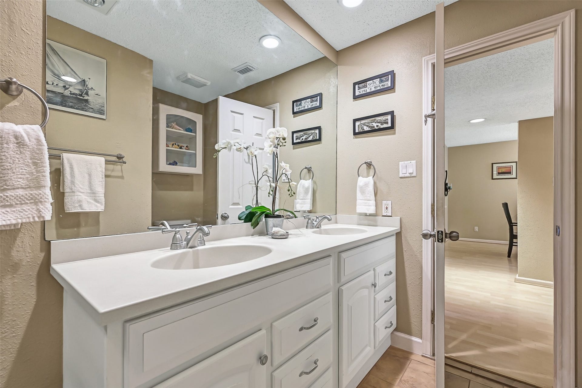 18214 Bal Harbour Drive, Nassau Bay, TX 77058 The remodeled second-floor bathroom features a dual-sink vanity with Silestone countertops, brushed-nickel fixtures, an oversized mirror & generous cabinet and drawer storage. A built-in curio cabinet adds additional storage, while the walk-in shower features custom tilework and thoughtful accessibility details.