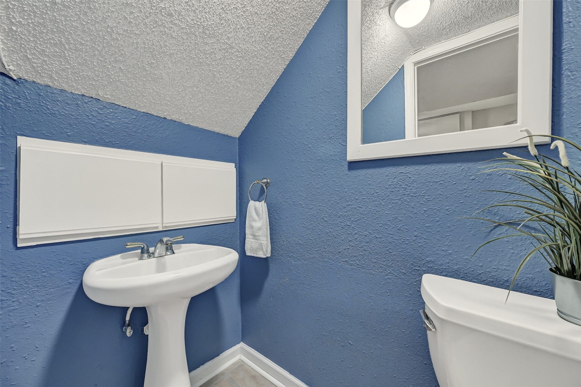 18214 Bal Harbour Drive, Nassau Bay, TX 77058 Conveniently located beside the ground-floor flex room, this half bath features a pedestal sink, framed mirror, updated lighting & tile flooring. The adjacent area is plumbed for a potential future tub or shower, offering an opportunity to expand the functionality of the ground-floor guest quarters.