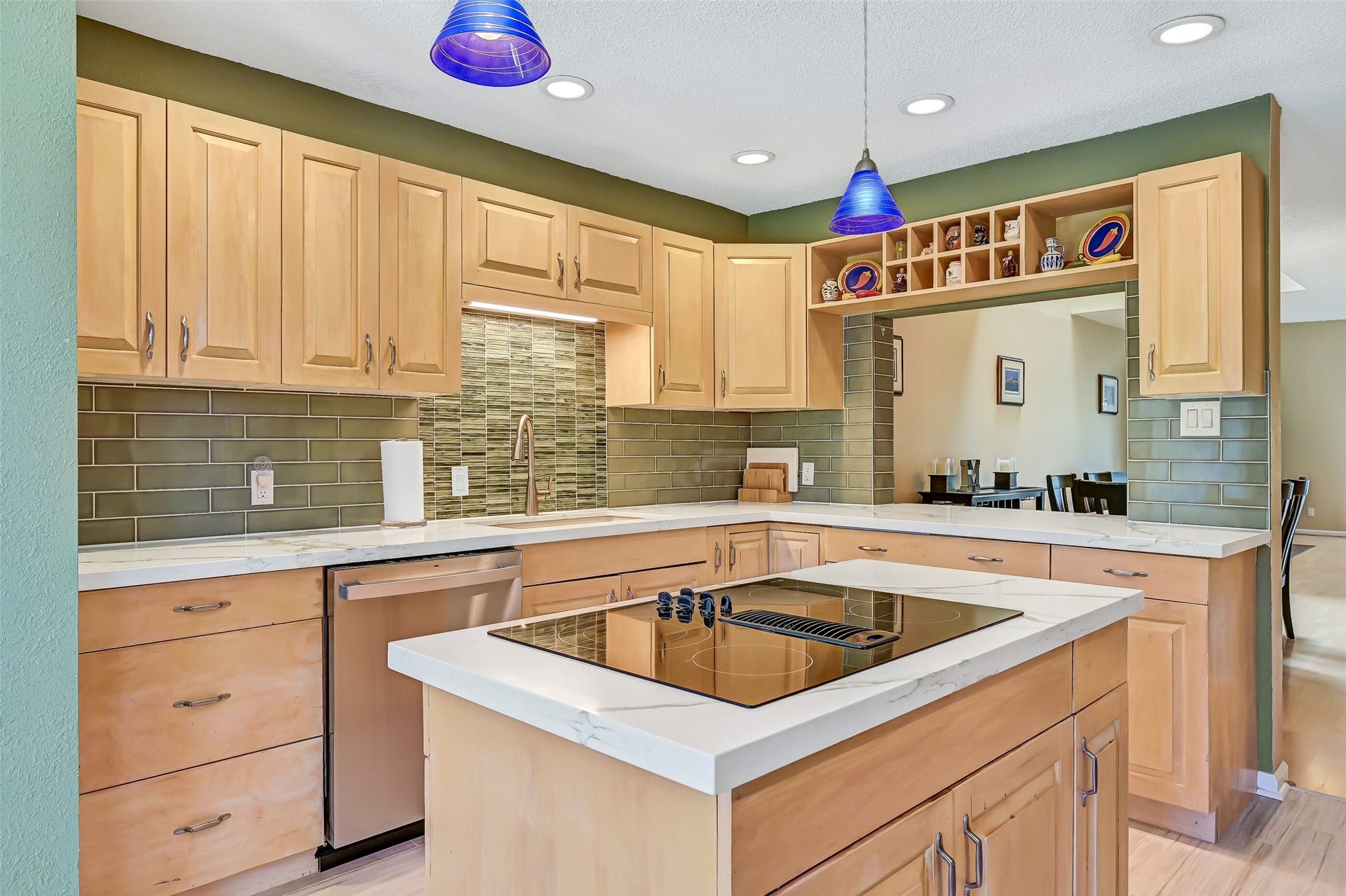 18214 Bal Harbour Drive, Nassau Bay, TX 77058 A closer look at the kitchen's generous cabinetry, quartz countertops & distinctive seafoam-green backsplash with glass tile accents behind the sink. The center island features a GE Profile glass cooktop with downdraft ventilation, Power Boil & Melt settings, while the pass-through serving bar connects to the separate dining area.