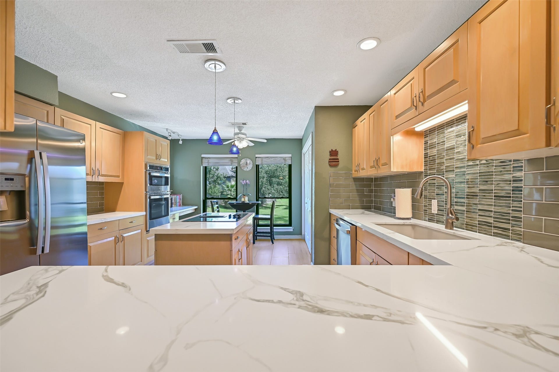 18214 Bal Harbour Drive, Nassau Bay, TX 77058 Looking toward the sunny breakfast area, the kitchen offers abundant counter space, light oak cabinetry, recessed lighting & updated tile flooring. The 2024 GE appliance package includes a stainless refrigerator with an icemaker, dishwasher, and built-in double oven featuring a microwave/oven combination and a full-size convection oven.