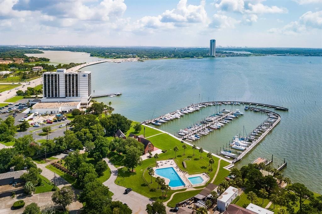 18214 Bal Harbour Drive, Nassau Bay, TX 77058 An aerial overview of Bal Harbour's waterfront setting along Clear Lake! The community marina, swimming pools, tennis courts & Windemere grounds are visible along the shoreline, with NASA Parkway and the former Hilton hotel, currently being transformed into a Compass by Margaritaville resort, just beyond.