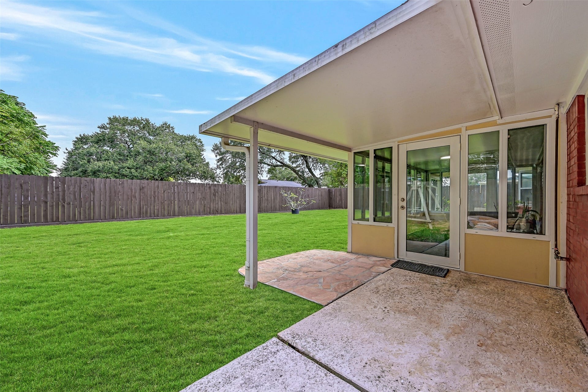 5403 Carmona Lane, Pearland, TX 77584 Step from the screened porch onto an additional covered patio overlooking the fenced backyard. The extended roofline provides a sheltered spot for grilling or outdoor seating, while the adjoining flagstone-style patio adds another place to gather and enjoy the yard.