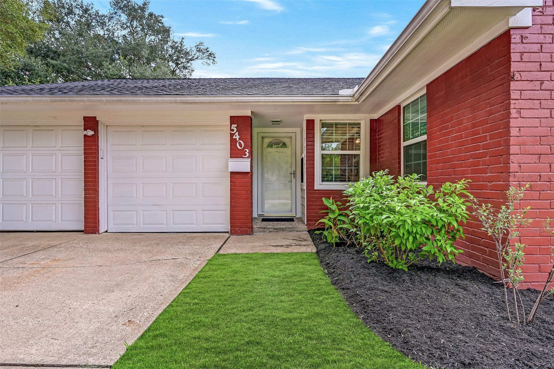 5403 Carmona Lane, Pearland, TX 77584 A closer look at the welcoming front entry, where fresh landscaping complements the painted brick exterior. A covered porch and full-view glass storm door lead inside, while the attached 2-car garage and double-wide driveway provide plenty of everyday parking.