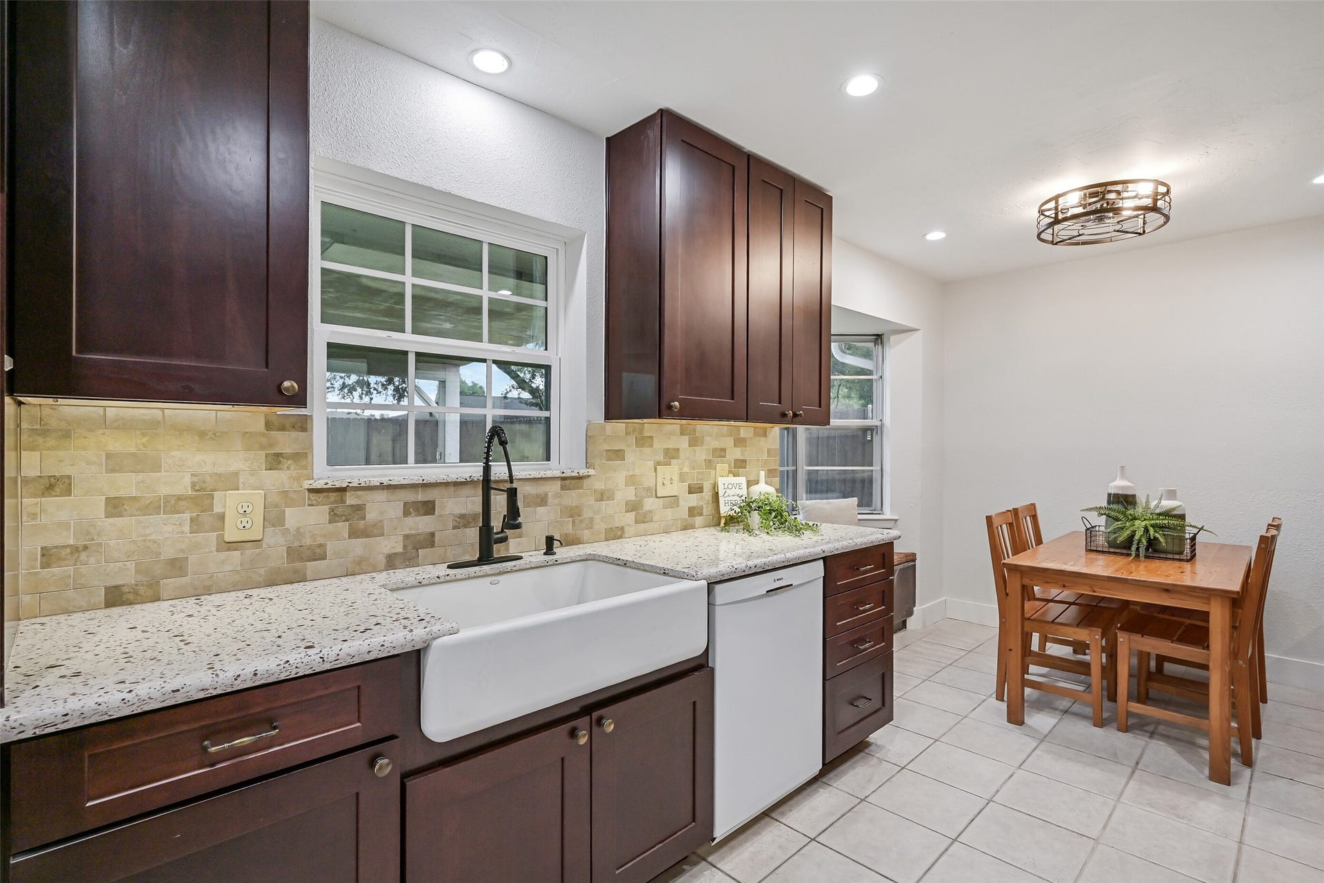 5403 Carmona Lane, Pearland, TX 77584 A single-basin porcelain apron-front sink pairs with a gooseneck faucet beneath a kitchen window, while granite counters & travertine backsplash continue along this side. Notice the multiple drawer stacks for easy-access storage, plus cabinetry extending beyond the kitchen into the breakfast room.