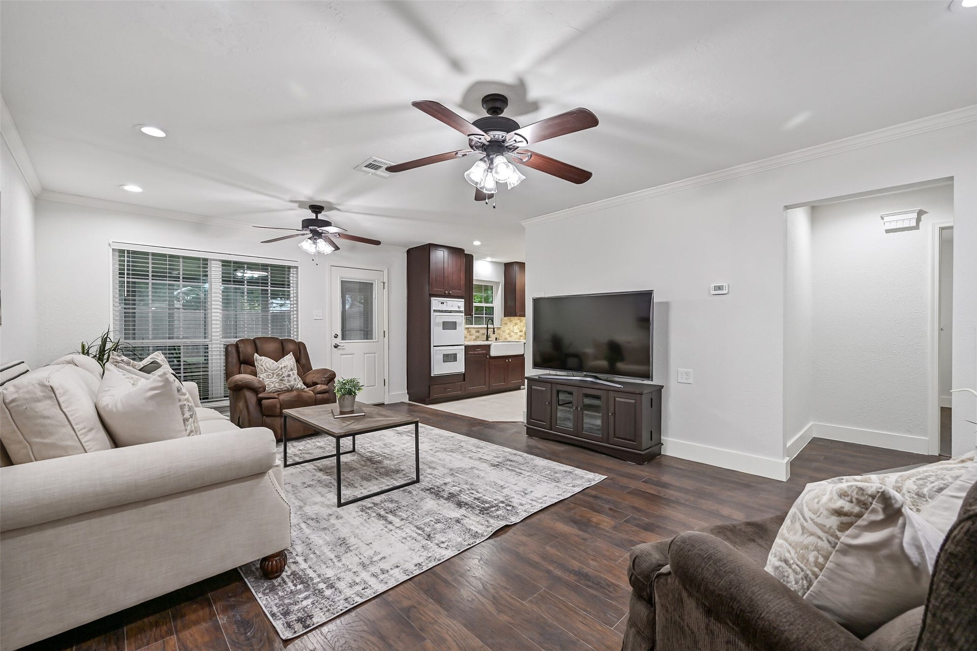 5403 Carmona Lane, Pearland, TX 77584 Step inside to a surprisingly spacious 21' x 14' family room with luxury vinyl plank flooring, fresh neutral paint, oversized baseboards, crown molding, recessed lighting & dual lighted ceiling fans. A large rear-facing window brings in natural light, while the open layout flows easily into the kitchen.
