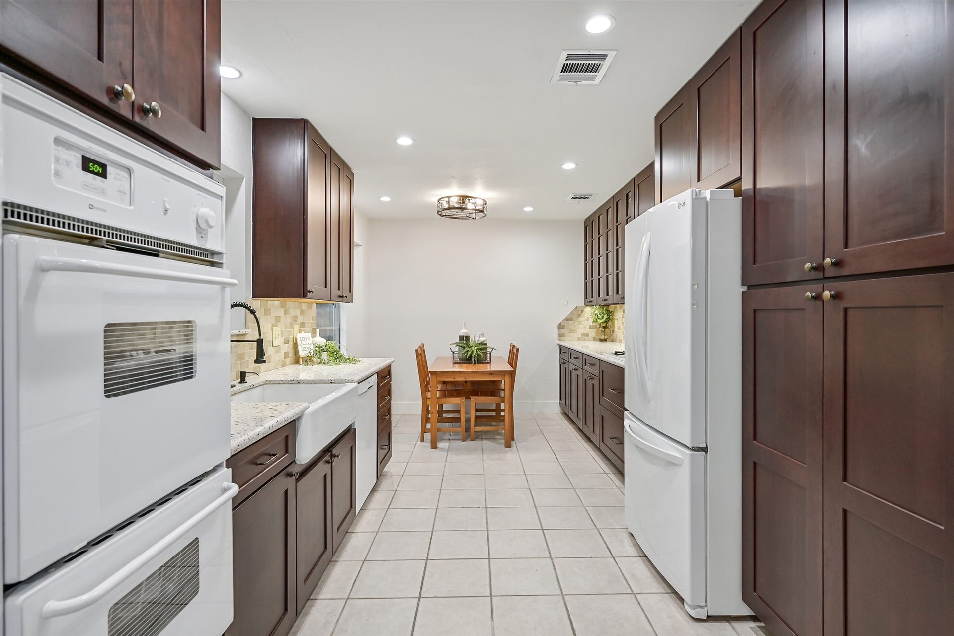 5403 Carmona Lane, Pearland, TX 77584 The updated kitchen offers an impressive amount of storage with rich soft-close cabinetry, glass-front accents & pots-and-pans drawers. Granite countertops, travertine backsplash, apron-front porcelain sink, double ovens & recessed lighting continue into the adjoining breakfast room.