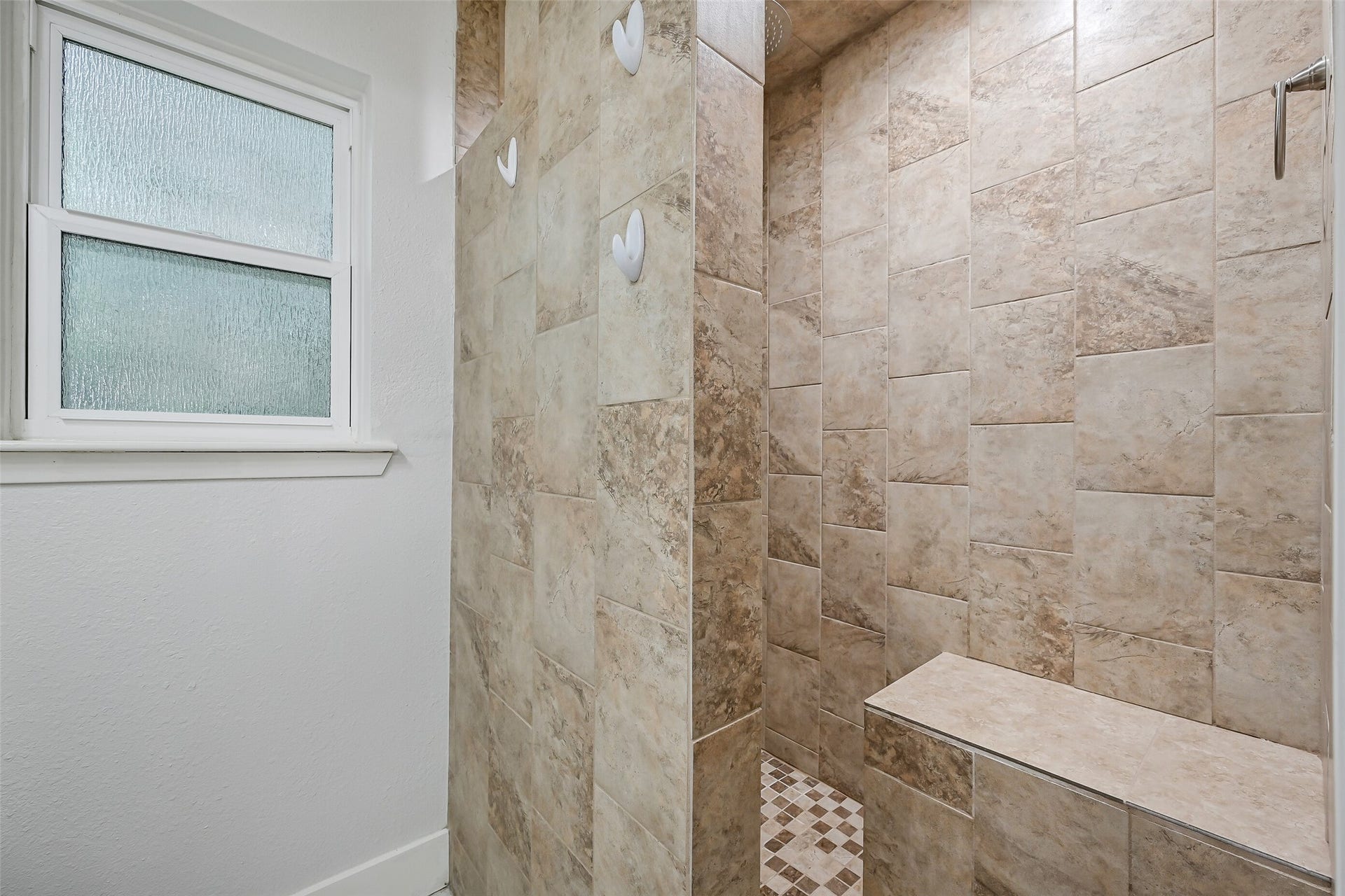 5403 Carmona Lane, Pearland, TX 77584 Step into the oversized walk-in shower, finished from floor to ceiling in warm-toned tile with a mosaic tile floor. A built-in bench offers convenient seating, while both an overhead rainfall showerhead & handheld shower provide a spa-inspired finishing touch.