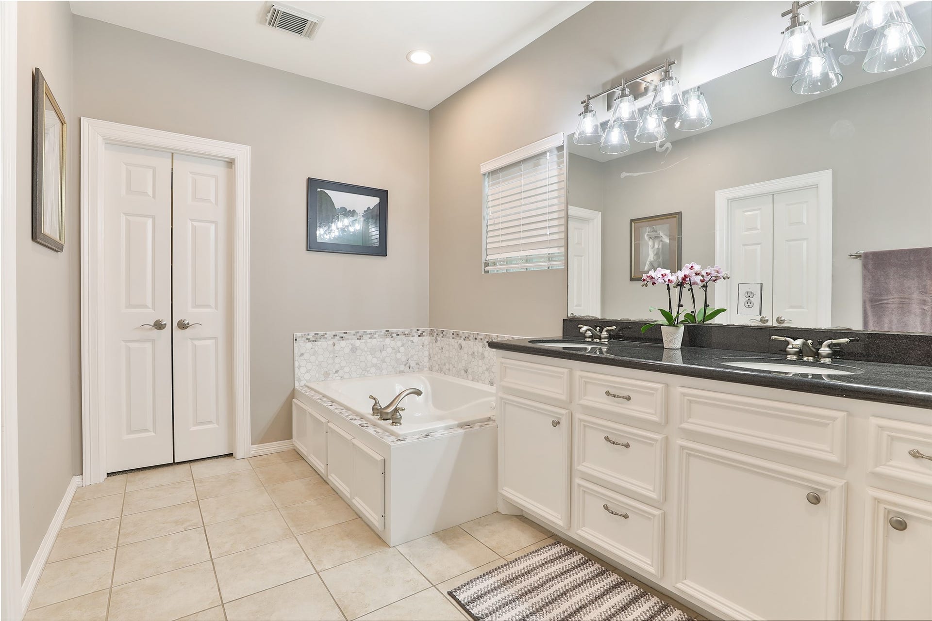Primary bathroom with dual sinks, a jetted tub, beautiful walk-in shower and two walk-in closets.