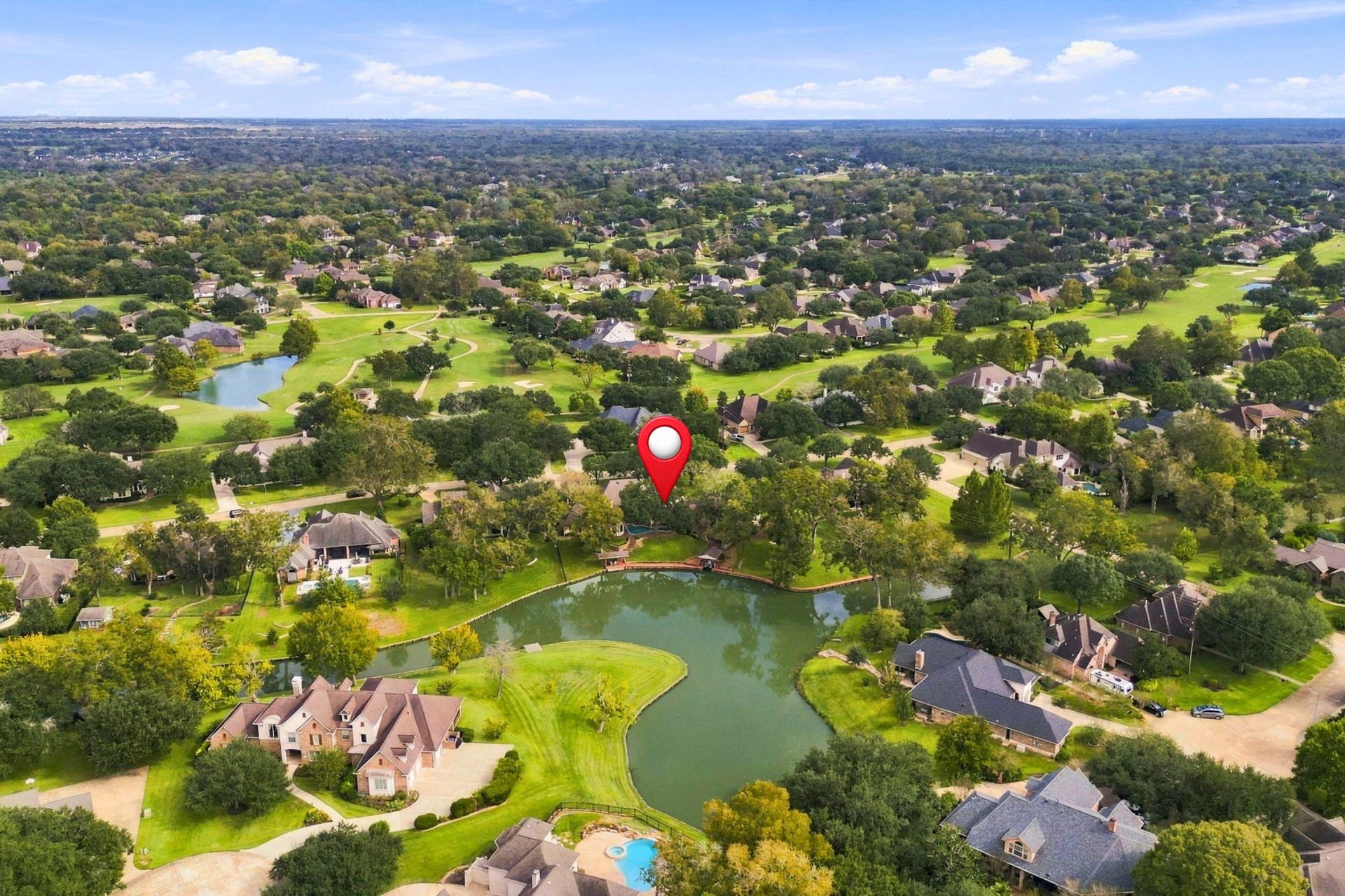 4711 Westerdale Drive, Fulshear, TX 77441 This view looks east toward the rear of the property, with the estate pinpointed for easy identification. The aerial perspective highlights its beautiful setting along Pecan Lake, with scenic views of the golf course in the distance.