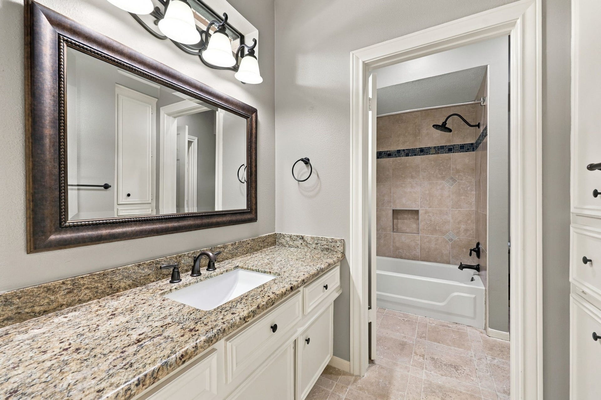 4711 Westerdale Drive, Fulshear, TX 77441 This side of the Jack-and-Jill Bathroom serves the bedroom featured in the previous photos and offers light cabinetry, granite countertops, an undermount sink, a framed mirror, and an oil-rubbed bronze widespread faucet. A tub and shower combination completes this well-appointed space.