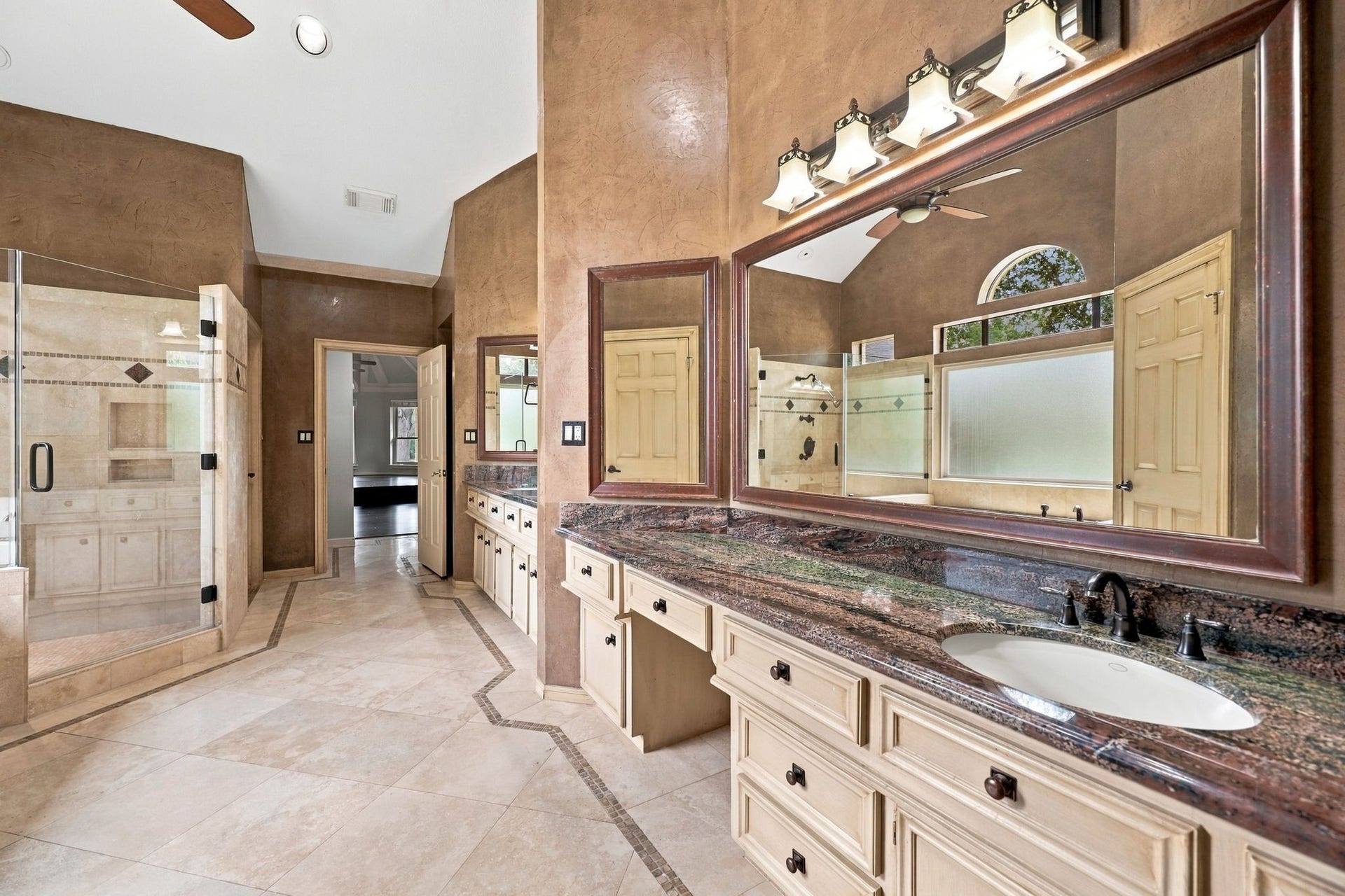 4711 Westerdale Drive, Fulshear, TX 77441 The second vanity area features a spacious granite countertop with an undermount sink, an oversized framed mirror, and elegant oil-rubbed bronze widespread faucets. Coordinating light fixtures complete the look, adding a warm and sophisticated touch to this beautifully appointed Primary Bath.