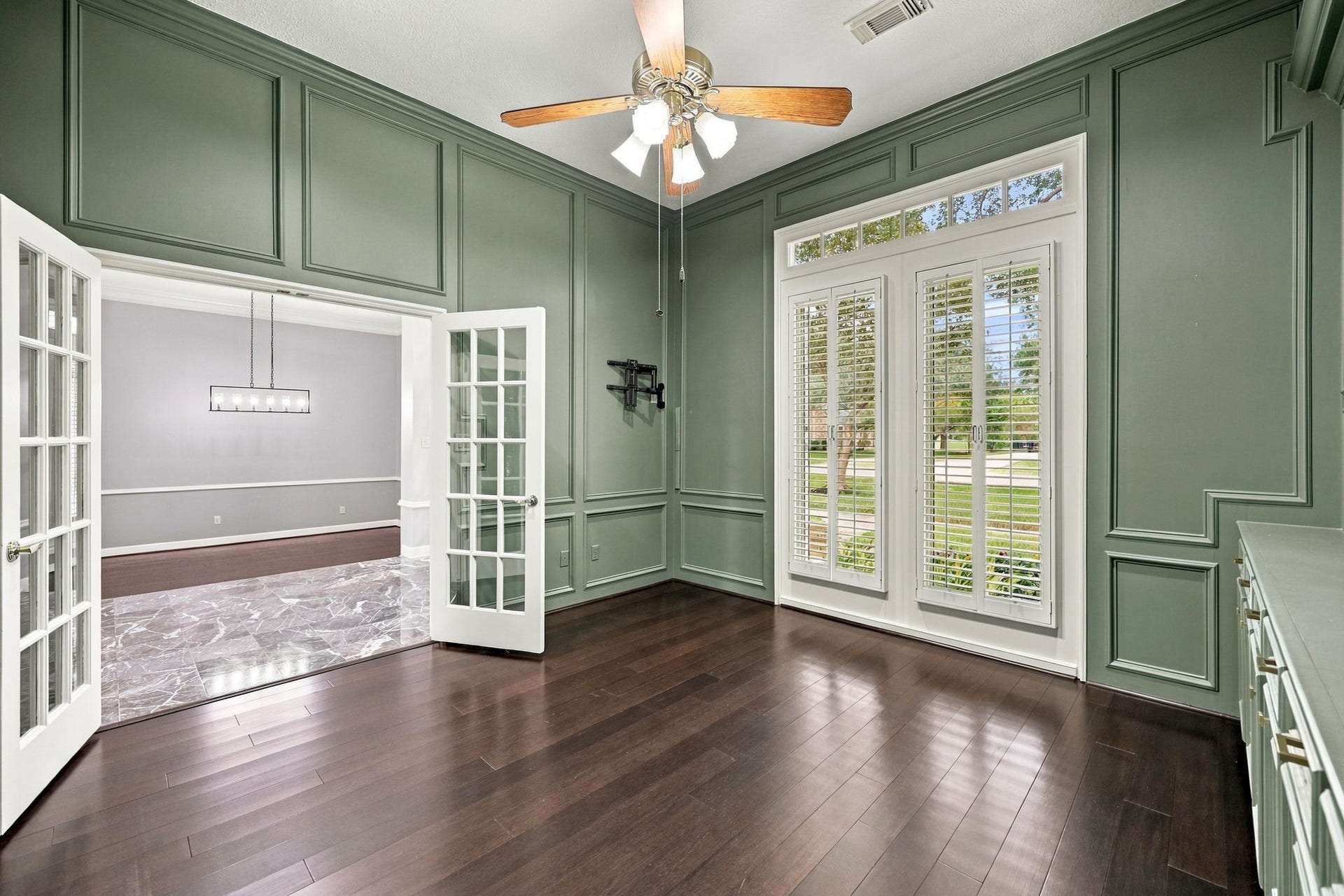 4711 Westerdale Drive, Fulshear, TX 77441 Located just off the main Foyer, the private Home Office is accessed through beautiful double glass-paneled doors, creating an elegant entrance while allowing natural light to flow into the space. The soothing mossy green paint color adds warmth and character, creating a calming yet sophisticated atmosphere.