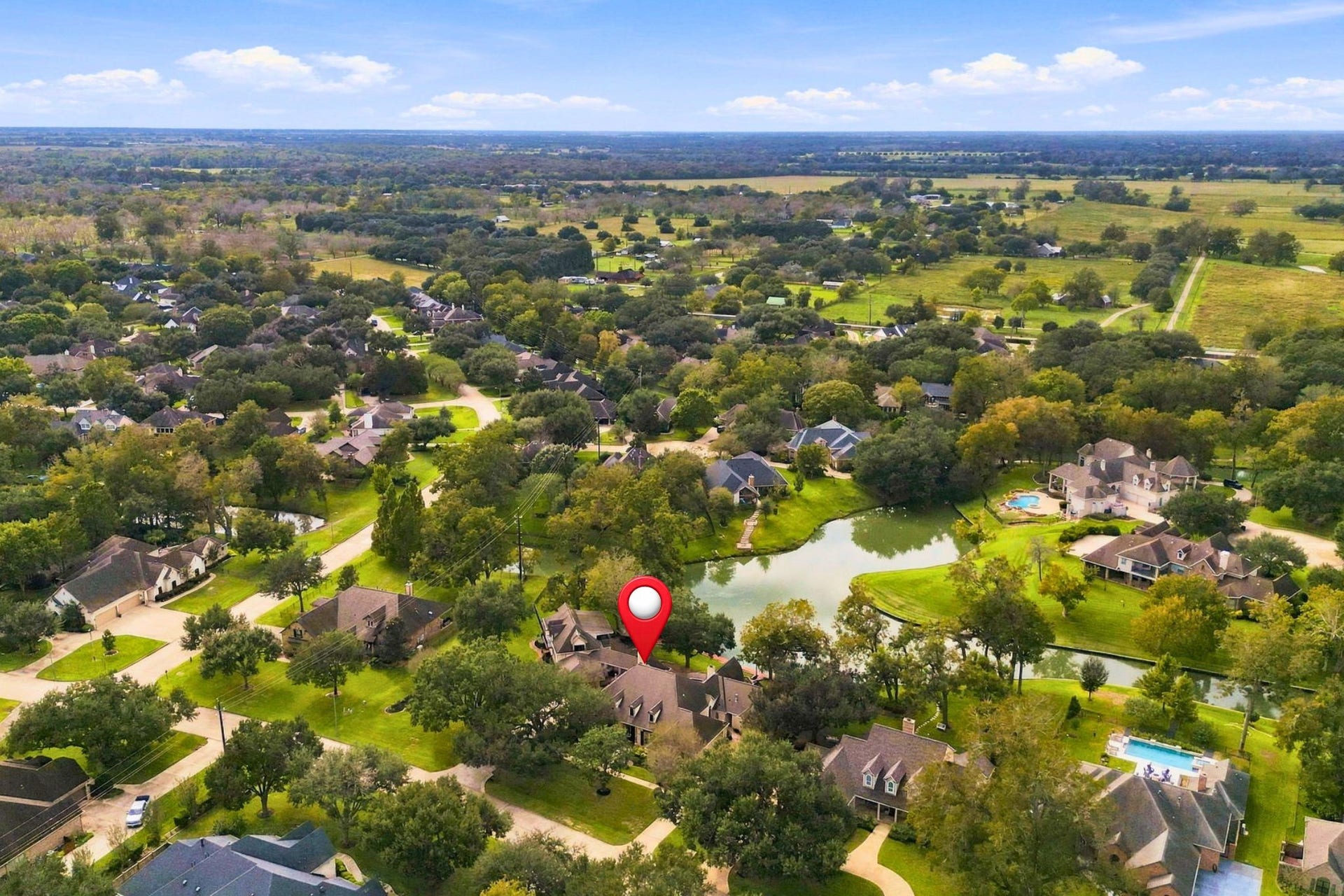 4711 Westerdale Drive, Fulshear, TX 77441 This aerial view looks west toward the front of the property, which is pinpointed for easy identification and to highlight its beautiful location within the community.