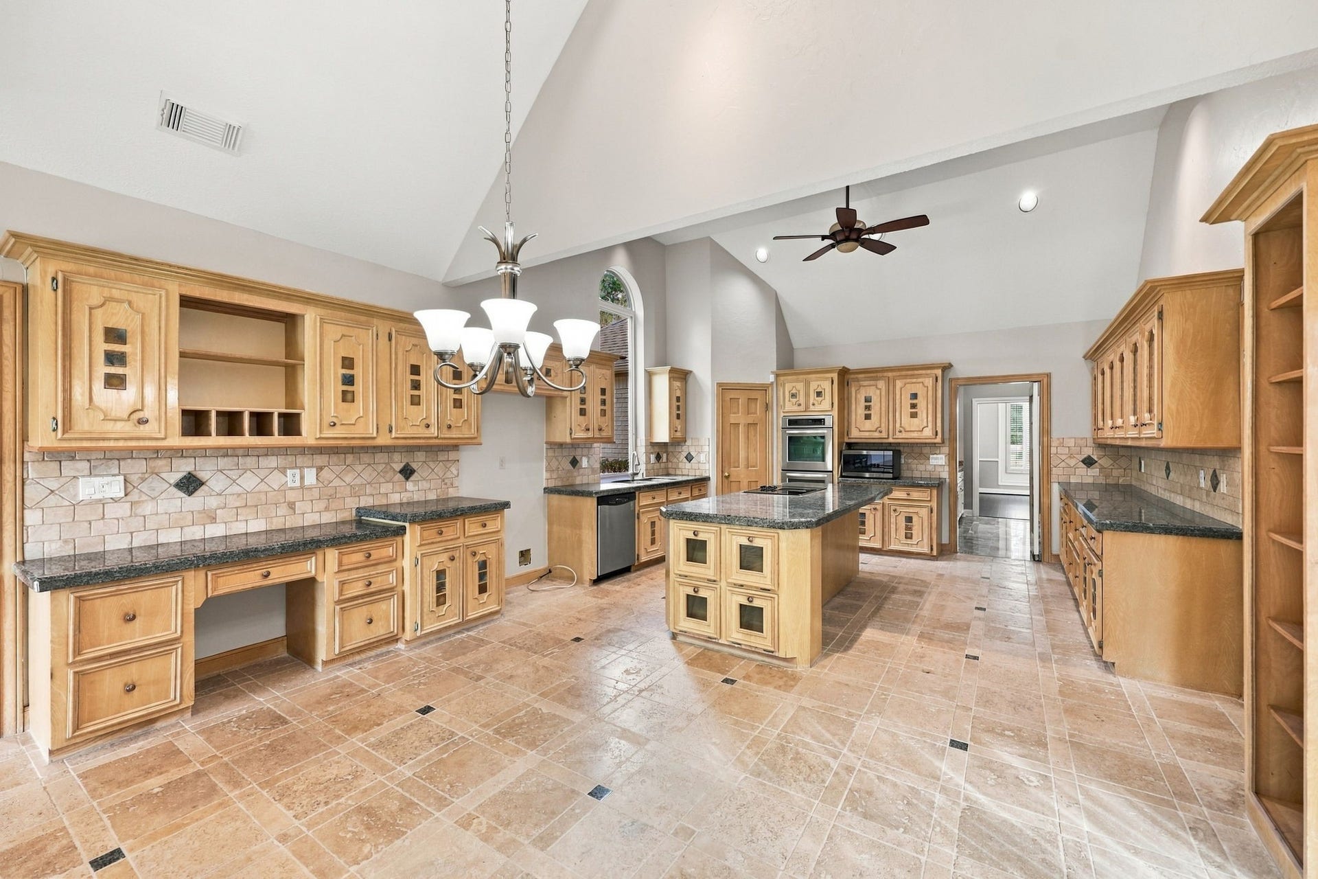 4711 Westerdale Drive, Fulshear, TX 77441 Looking in the opposite direction, you'll discover a convenient built-in desk area, offering an additional workspace perfect for managing household tasks, studying, or working from home. The Kitchen is beautifully appointed with tile flooring featuring a decorative pattern of varying tile sizes and accent pieces, gorgeous granite countertops, and a coordinating backsplash that completes the look.