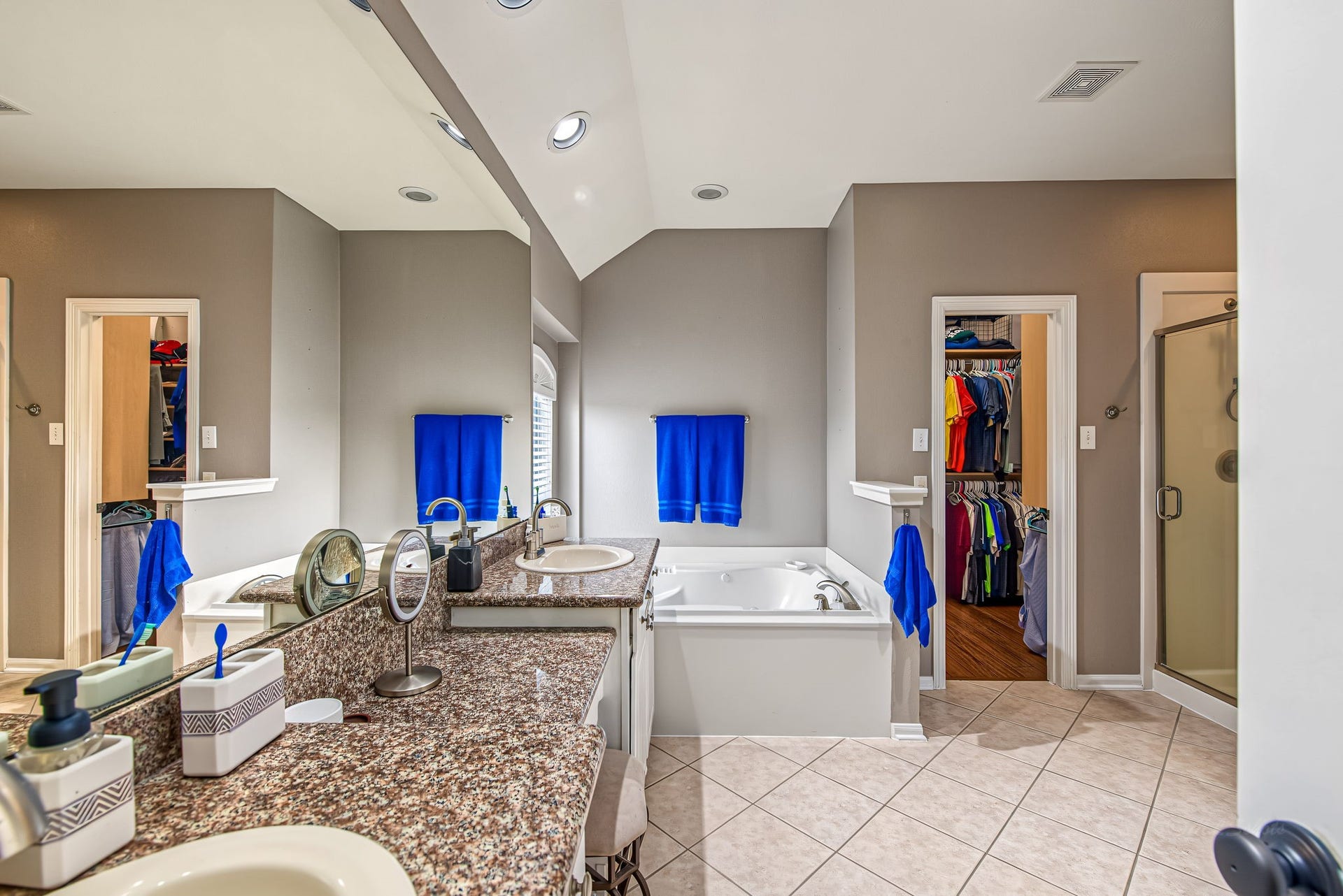 21223 Dover Park Lane, Katy, TX 77450 Spacious bathroom featuring a luxurious soaking tub, dual sinks with granite countertops, and a separate glass-enclosed shower, complemented by adjacent walk-in closets.