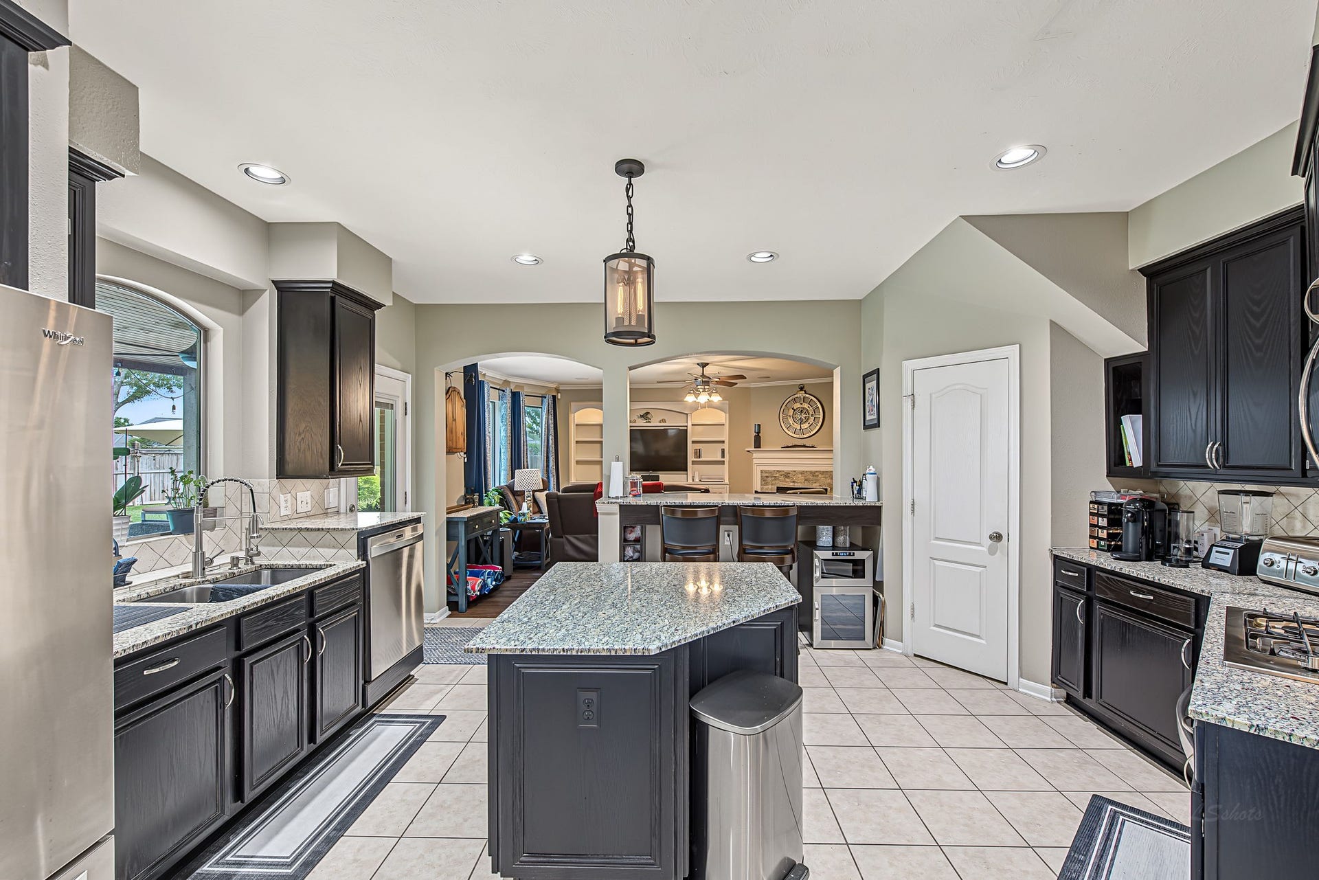 21223 Dover Park Lane, Katy, TX 77450 Spacious kitchen with sleek dark cabinetry, granite countertops, and a central island. Open layout flows into the cozy living area, perfect for entertaining. Natural light streams through large windows, enhancing the inviting atmosphere.