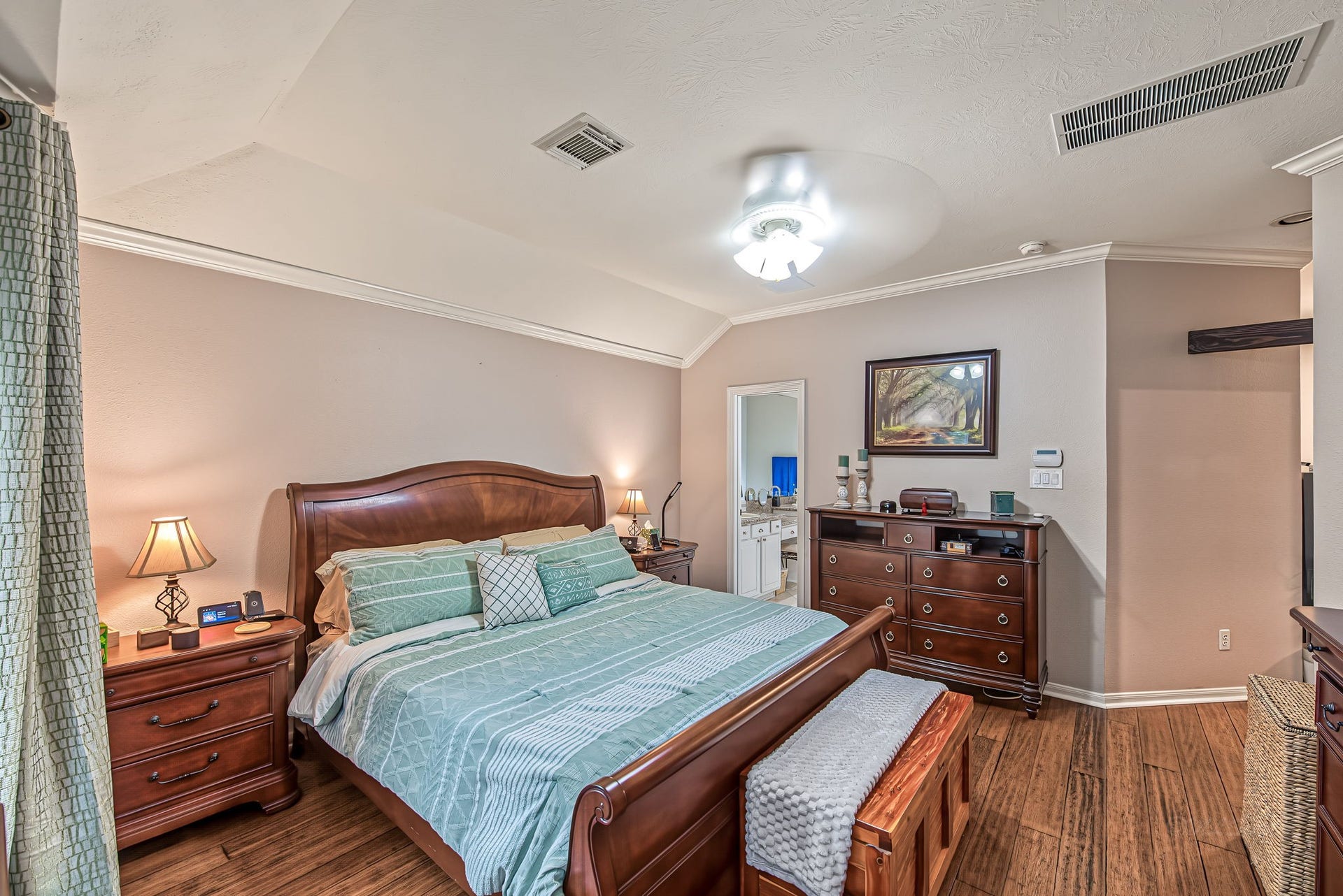 21223 Dover Park Lane, Katy, TX 77450 Spacious bedroom with elegant wood furnishings, featuring a large bed, matching nightstands, and a dresser, complemented by soft lighting and warm, inviting decor.