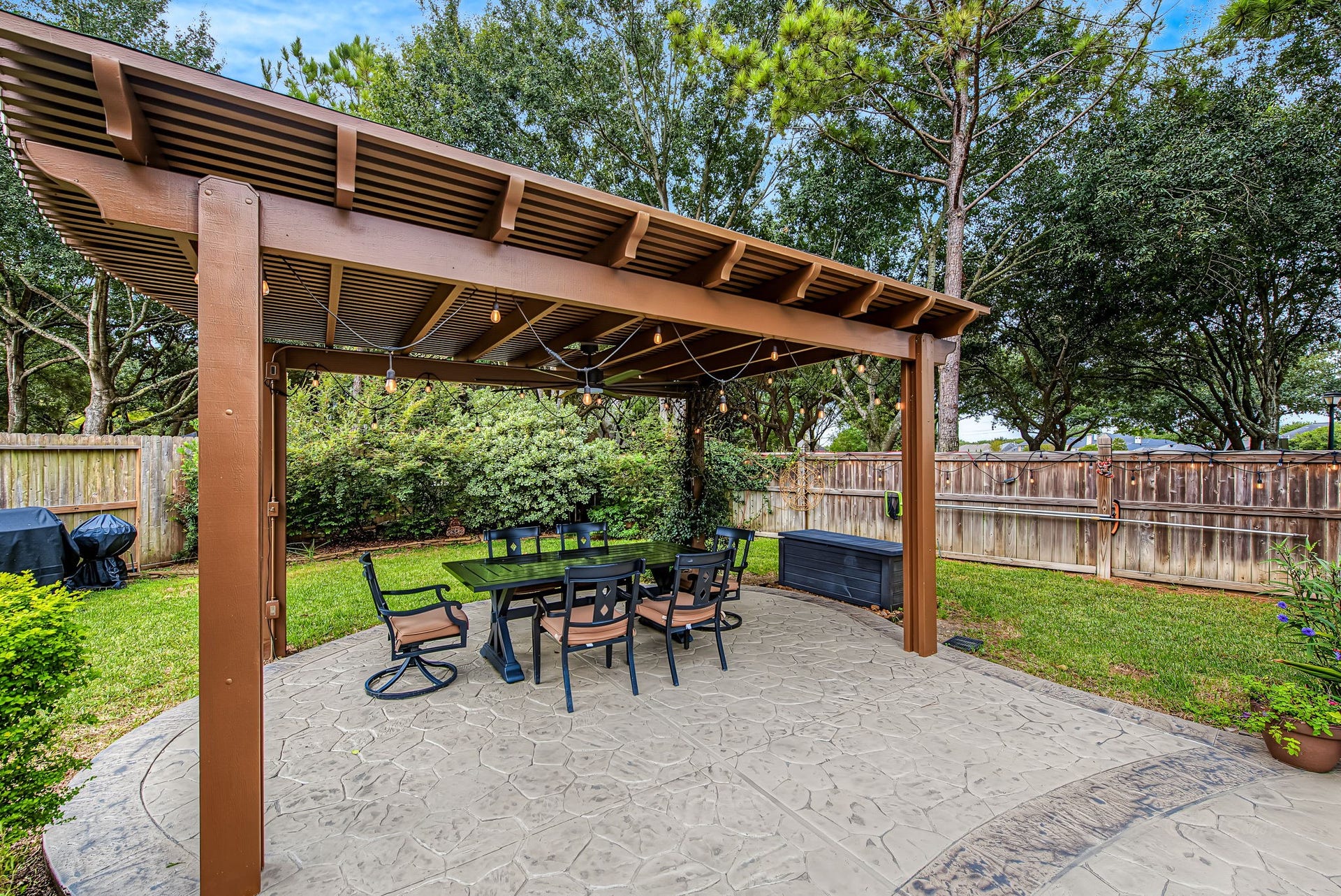 21223 Dover Park Lane, Katy, TX 77450 Charming backyard with a spacious pergola, perfect for outdoor dining and entertaining, set against a lush, tree-lined fence for added privacy.