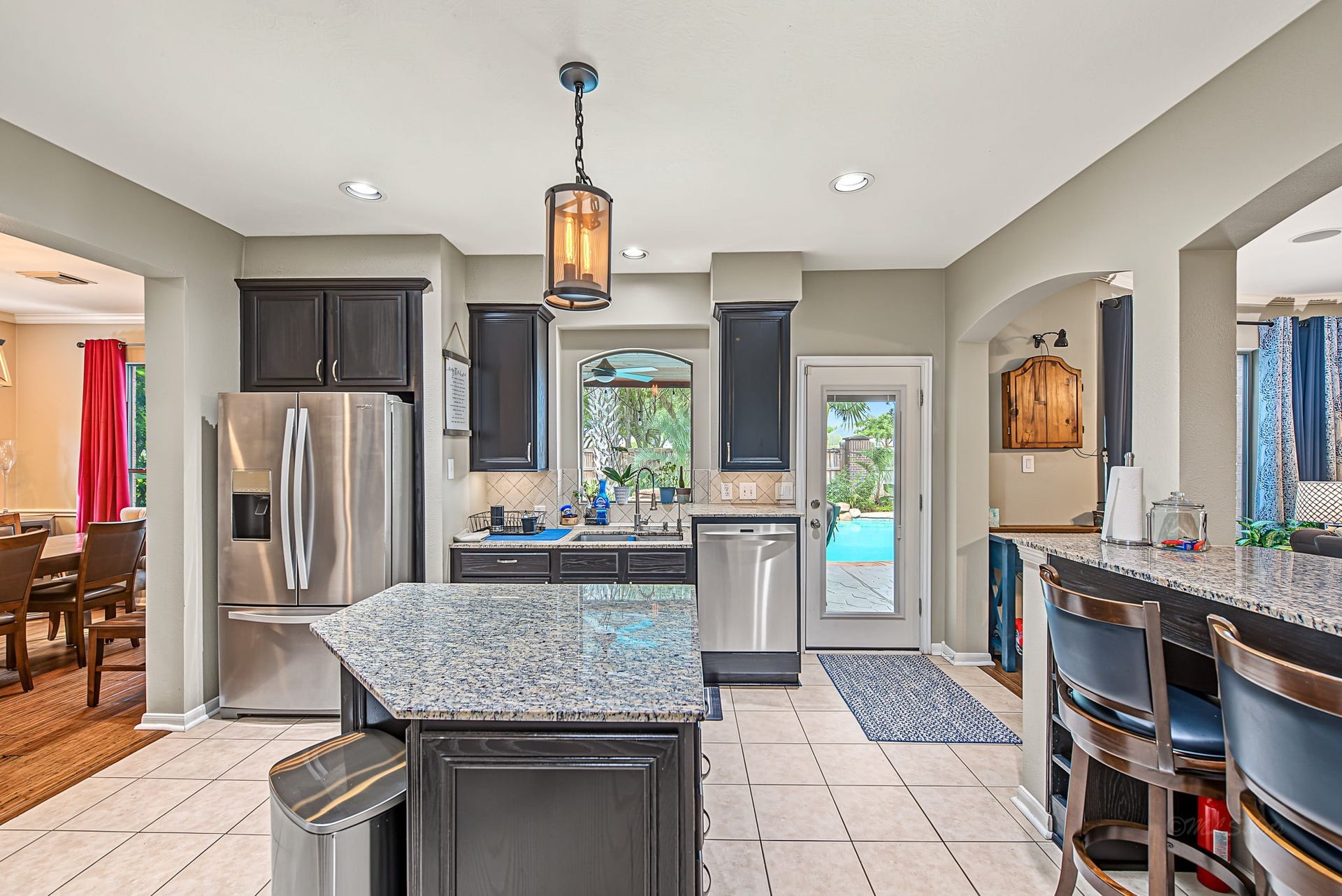 21223 Dover Park Lane, Katy, TX 77450 Spacious kitchen with granite countertops, modern stainless steel appliances, and island seating. Features a view of the pool through the glass door, providing a seamless indoor-outdoor experience.