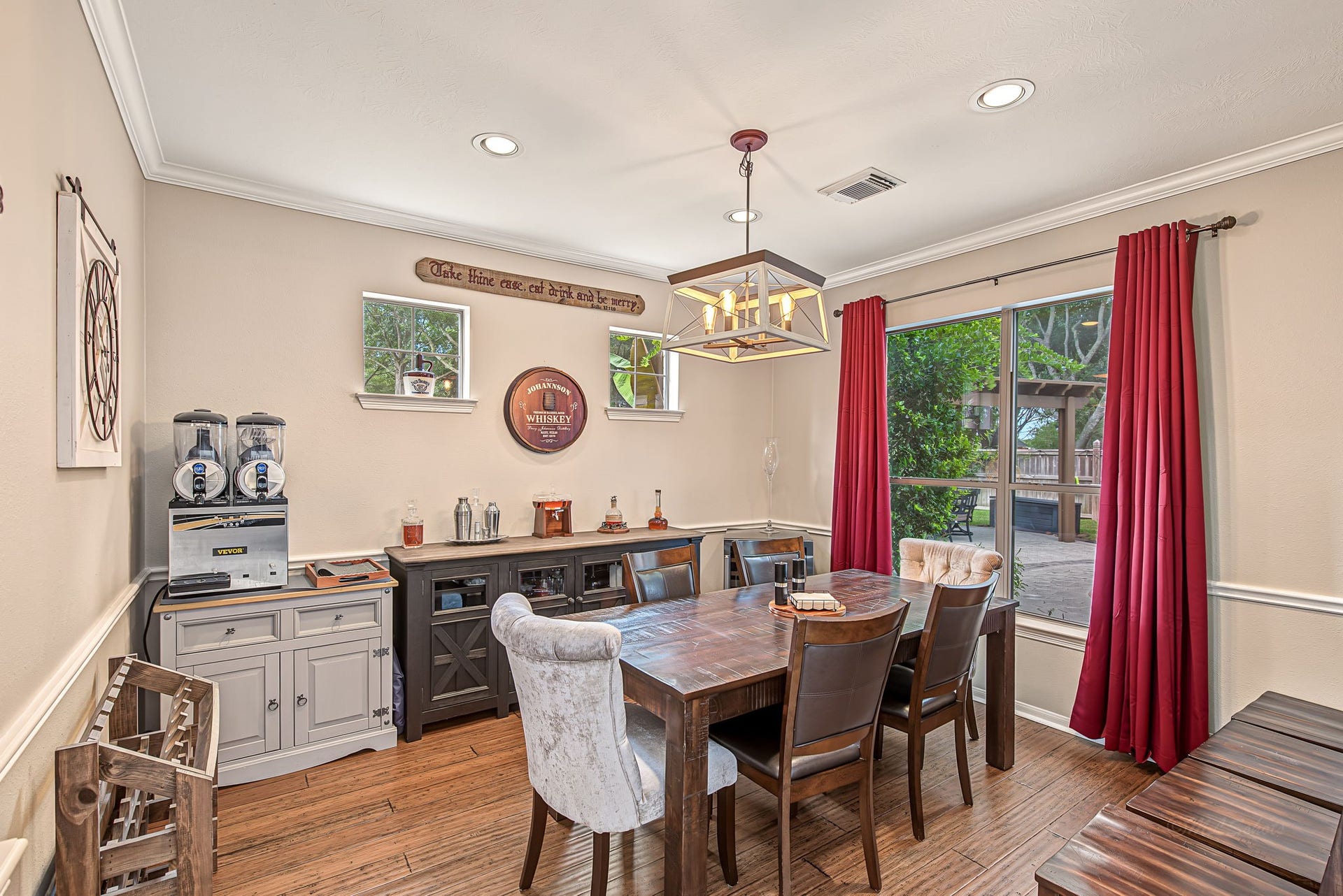 21223 Dover Park Lane, Katy, TX 77450 Charming dining room with rich wood flooring, a stylish light fixture, and large window with vibrant red curtains overlooking the lush backyard.