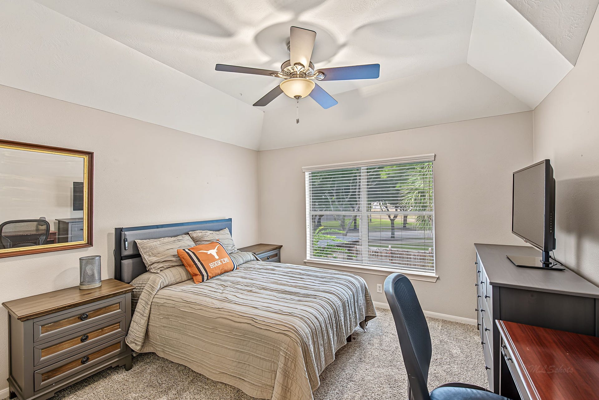 21223 Dover Park Lane, Katy, TX 77450 Bright and cozy bedroom featuring a vaulted ceiling with a ceiling fan, large window with lush views, and ample space for relaxation.