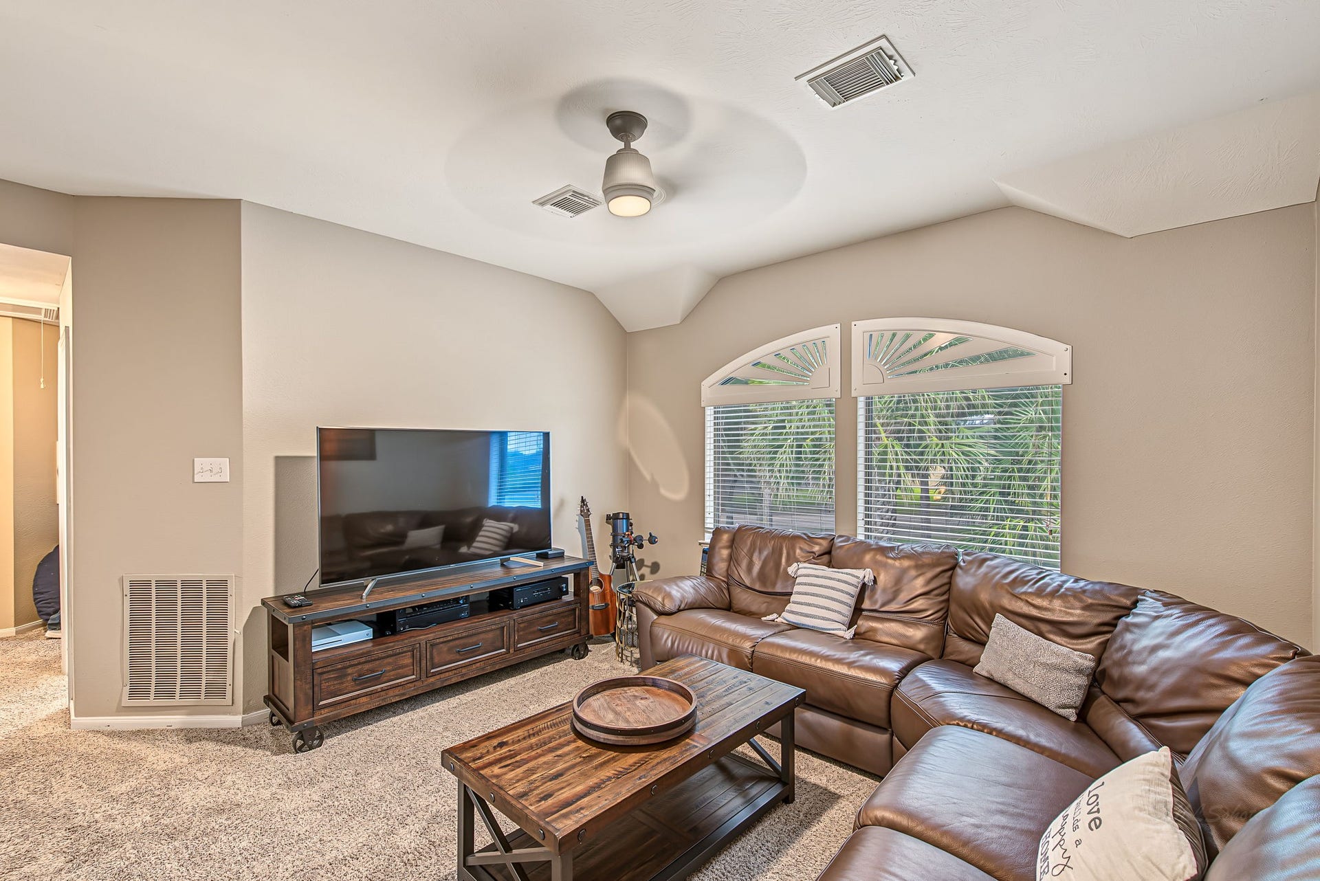 21223 Dover Park Lane, Katy, TX 77450 Cozy living room featuring a plush leather sectional, large TV, and natural light from stylish arched windows, perfect for relaxation and entertainment.