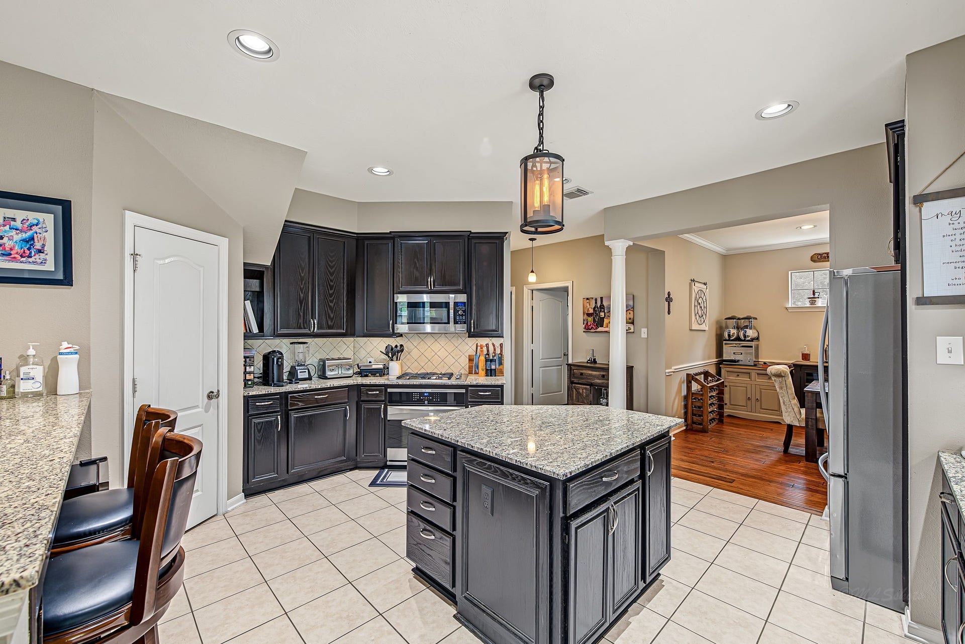 21223 Dover Park Lane, Katy, TX 77450 Elegant kitchen with dark wood cabinets, granite countertops, and a central island, seamlessly opening to a cozy dining area.